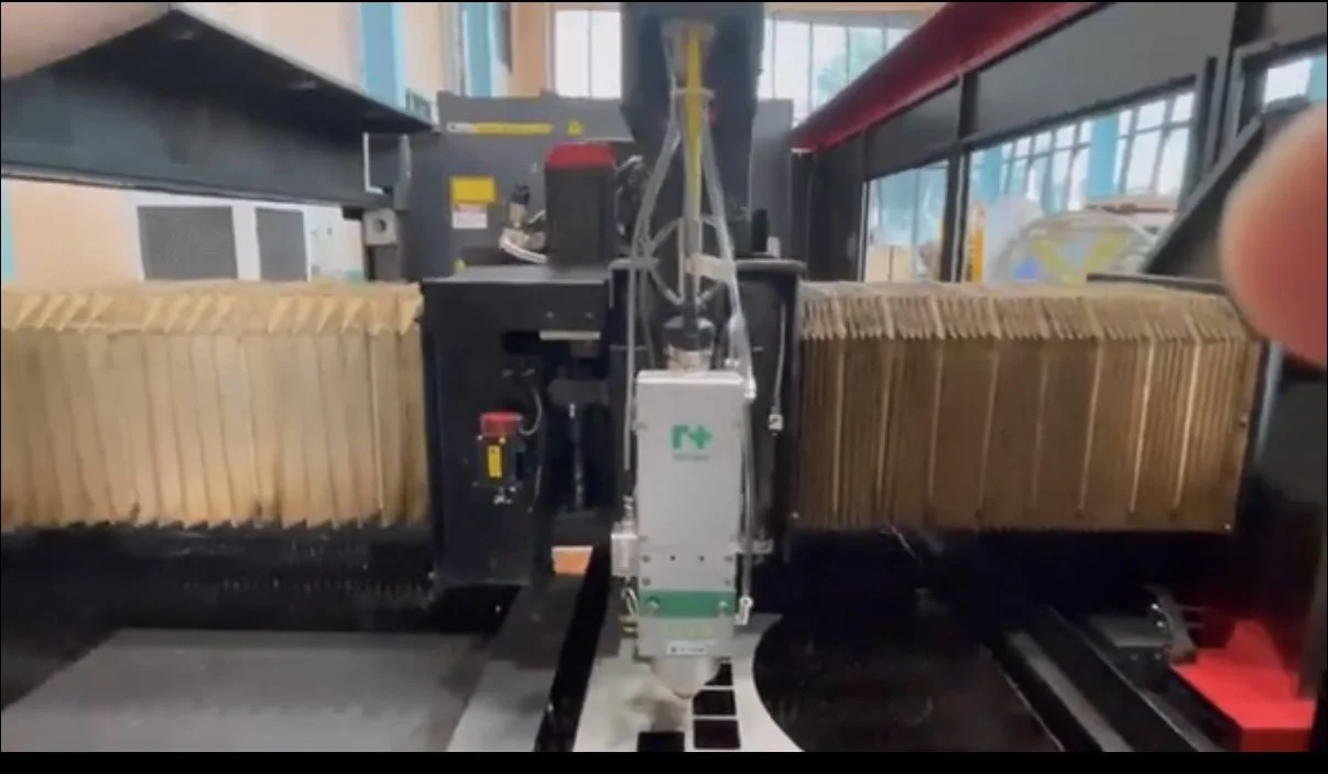 Close-up view of an industrial machine cutting or manufacturing cardboard packing materials in a factory setting.