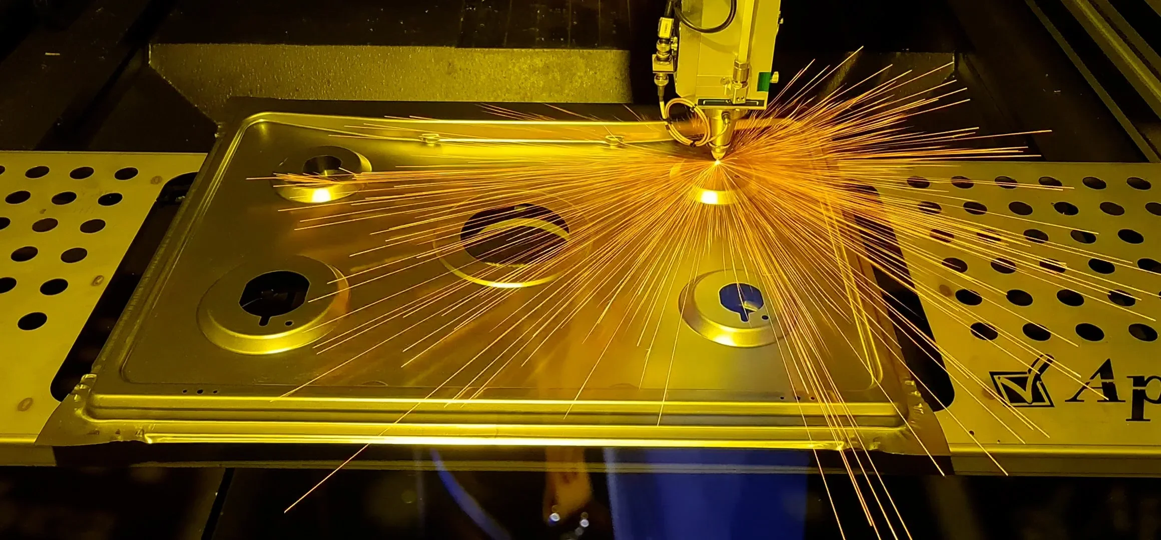 A laser cutting machine cutting through a metal sheet, creating bright sparks and glowing edges.