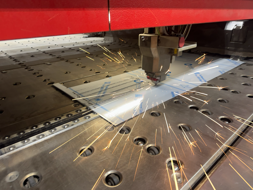 A laser cutting machine cutting metal sheet, sparks flying, working on a metal table.