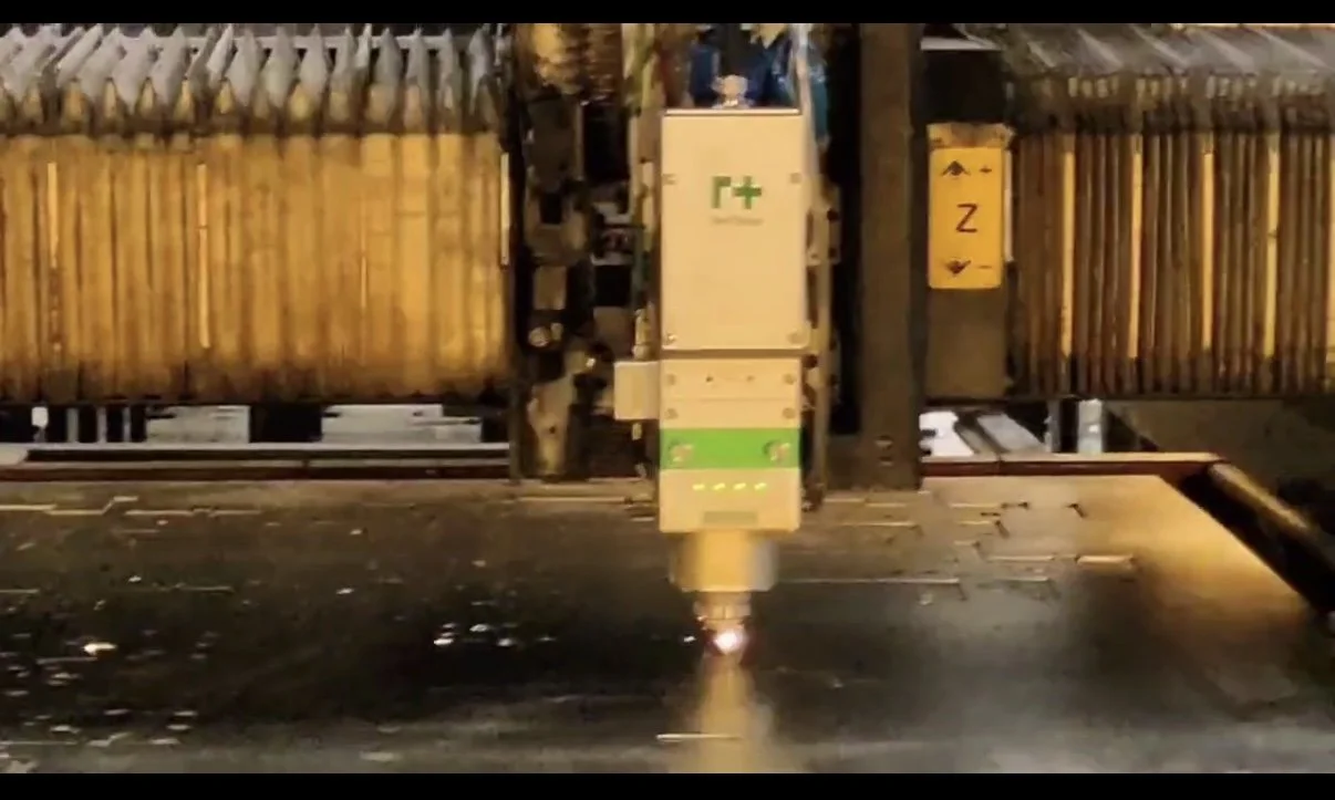 A robotic welding arm working on a metal surface with sparks flying.