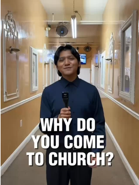 Joven con camisa azul sosteniendo un micrófono en un pasillo decorado con paredes color mostaza y cuadros blancos, con la leyenda '¿Por qué vienes a la iglesia?'