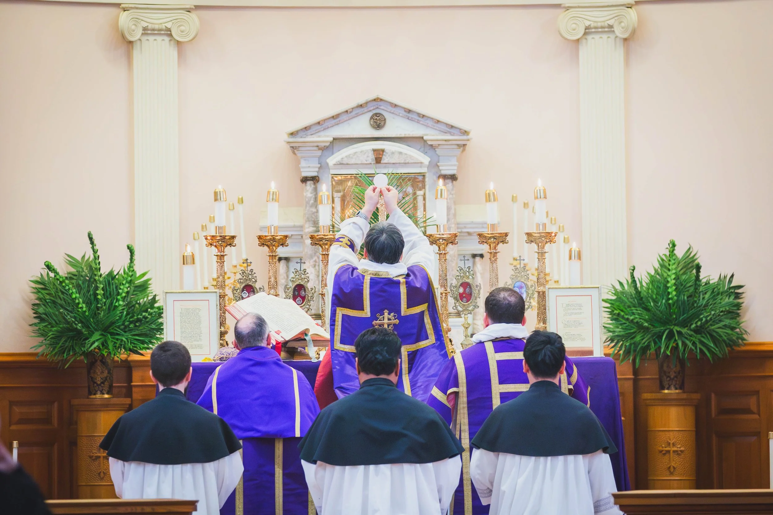 A Dominican rite Solemn High Mass during Palm Sunday with a priest, deacon and subdeacon in Holy Rosary Parish in Portland, OR during the elevation of the host. 