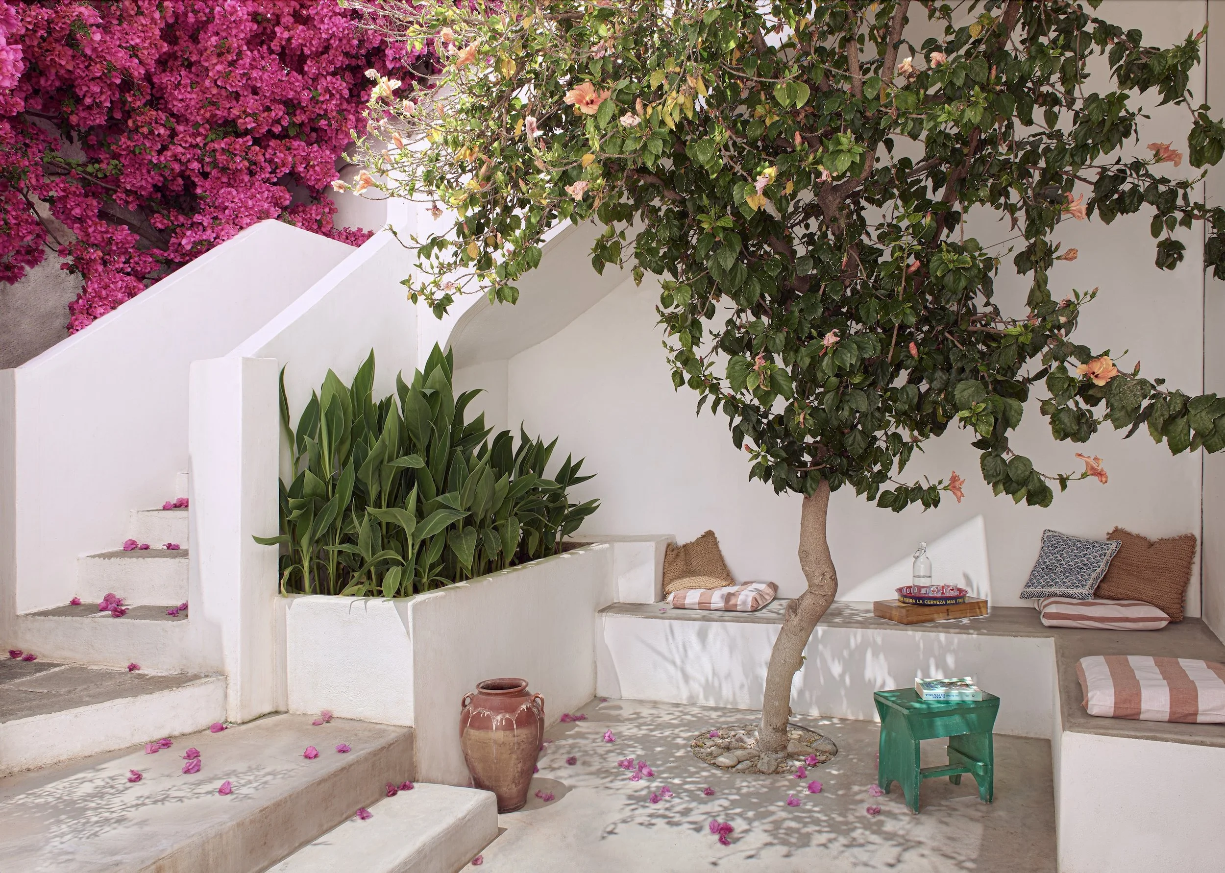 Mediterranean courtyard garden in a Greek island house on Serifos with white walls, a lemon tree, and red striped cushions, designed by Howark Design.
