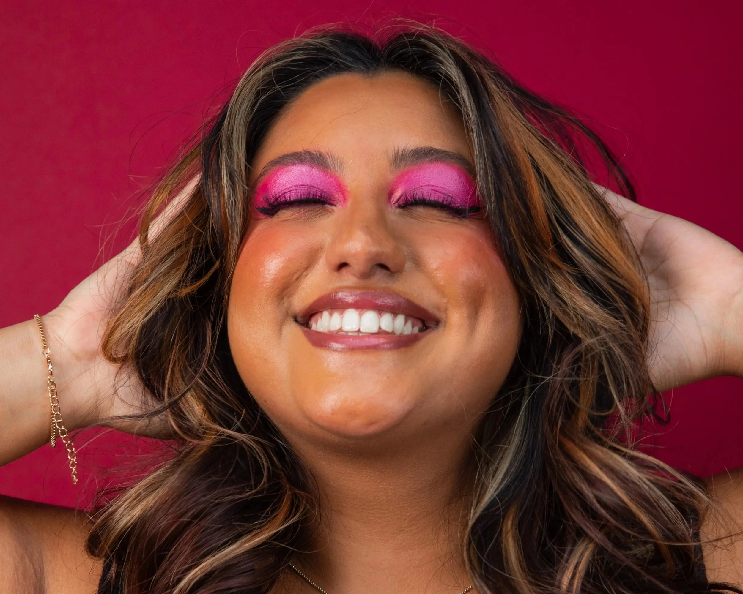 Shareena has her head tilted back slightly with her eyes closed and both hands behind her head.