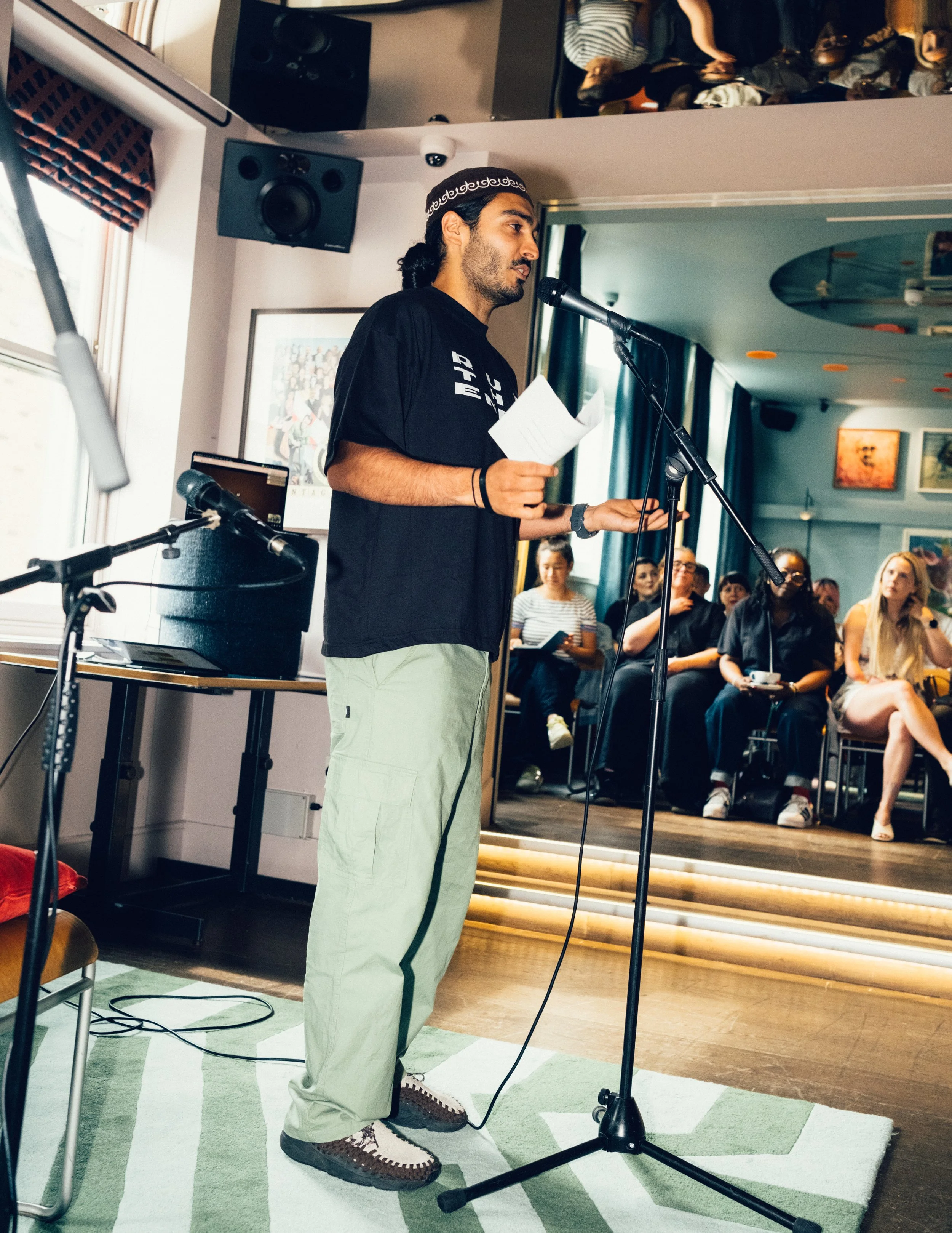 Presenter and host Moeed stood, speaking into a microphone at an event