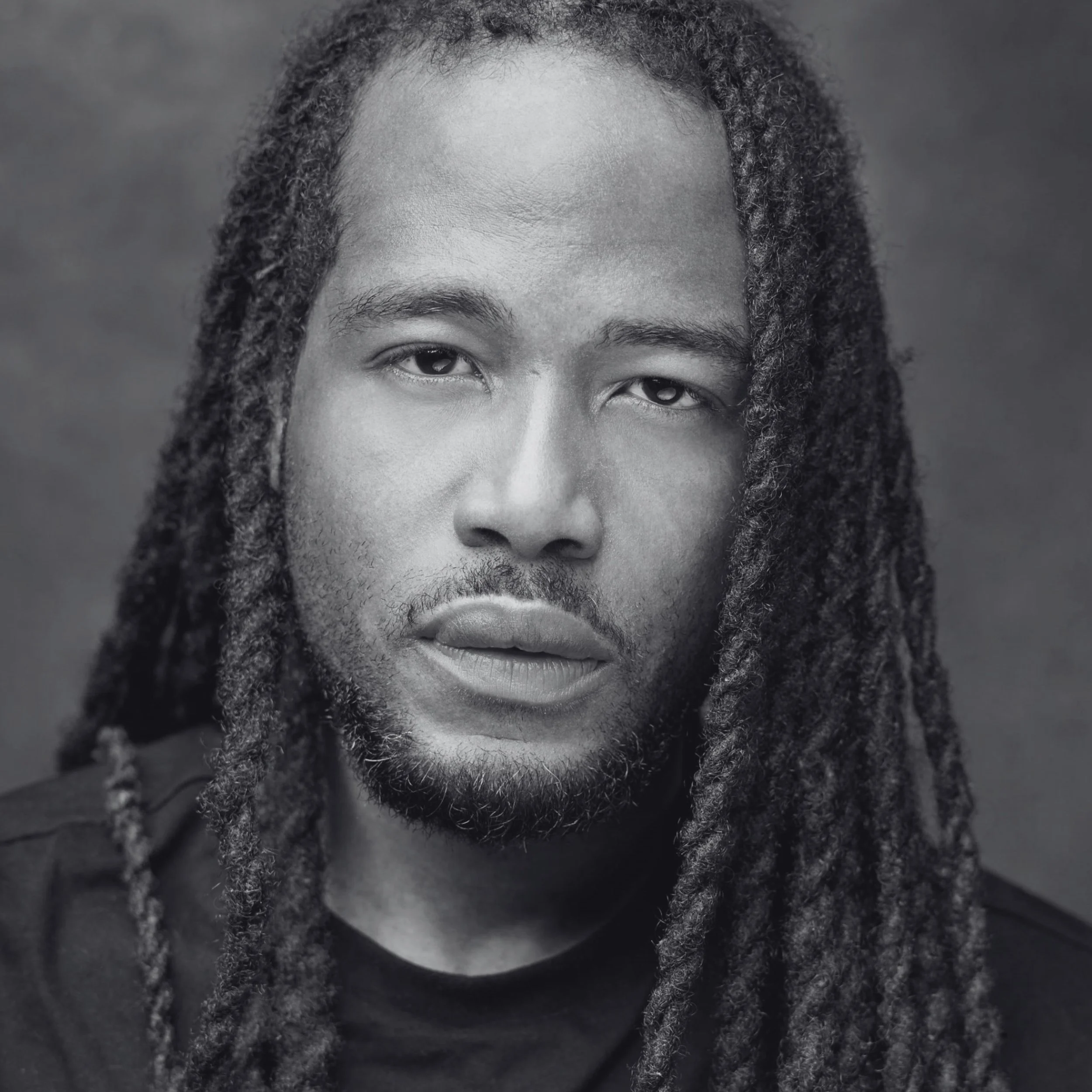 Ekow is a Black man with long dark dreadlocks. He has brown eyes and a beard.