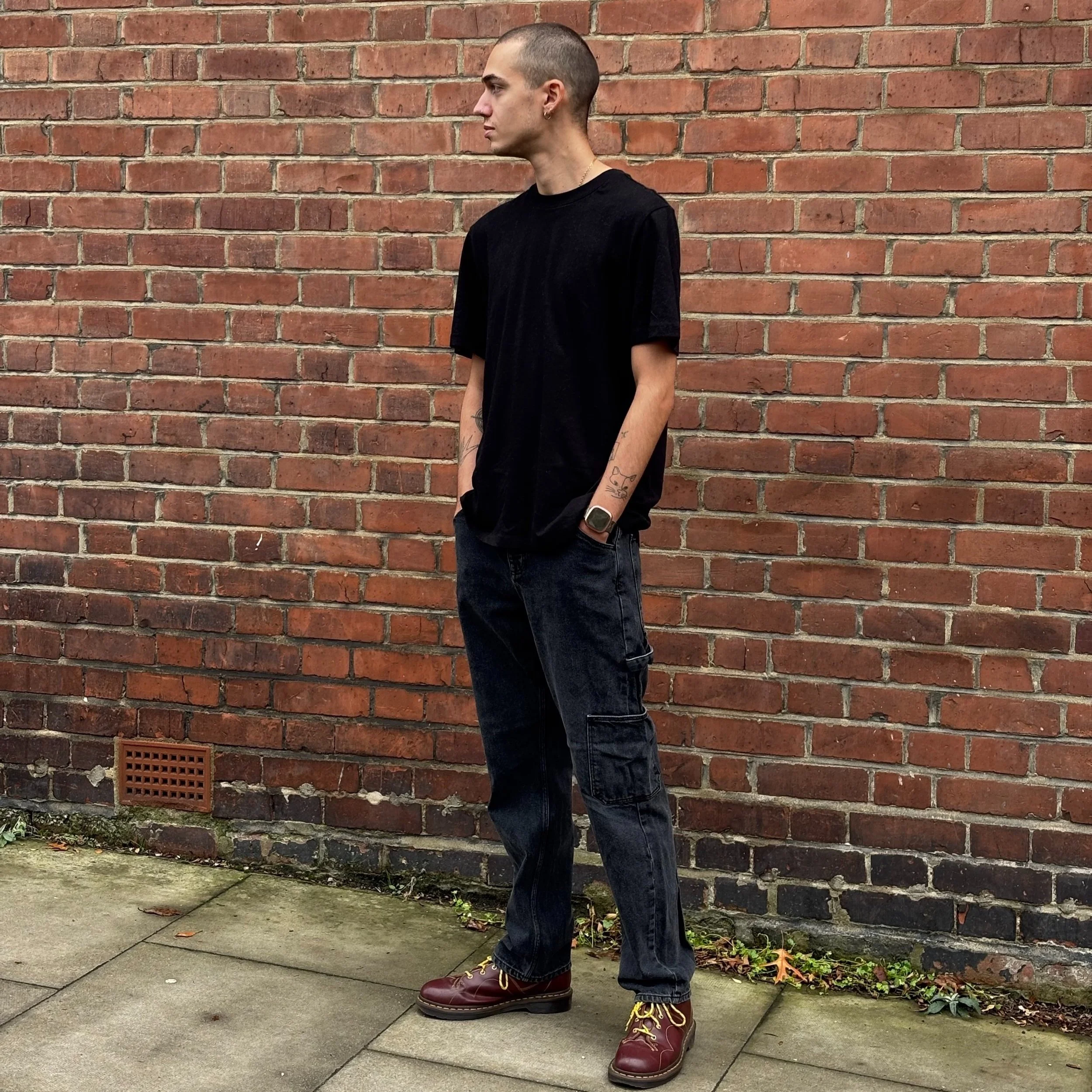 Charles is a white man in his twenties with a shaved head. He has a nose ring, green eyes and wears a black tee and jeans