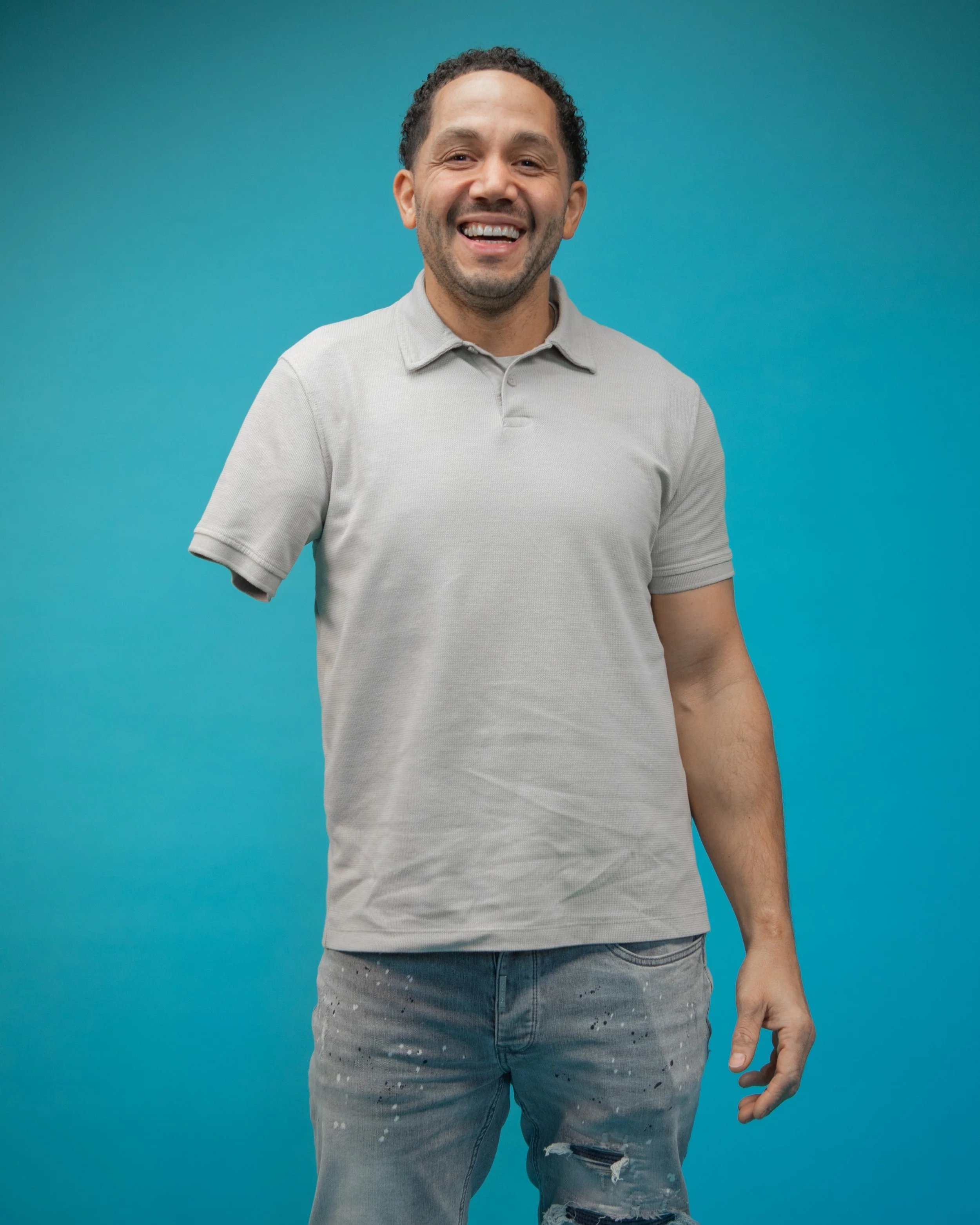 Another image from the same shoot - Chris is stood facing the camera smiling widely with his arm by his side.