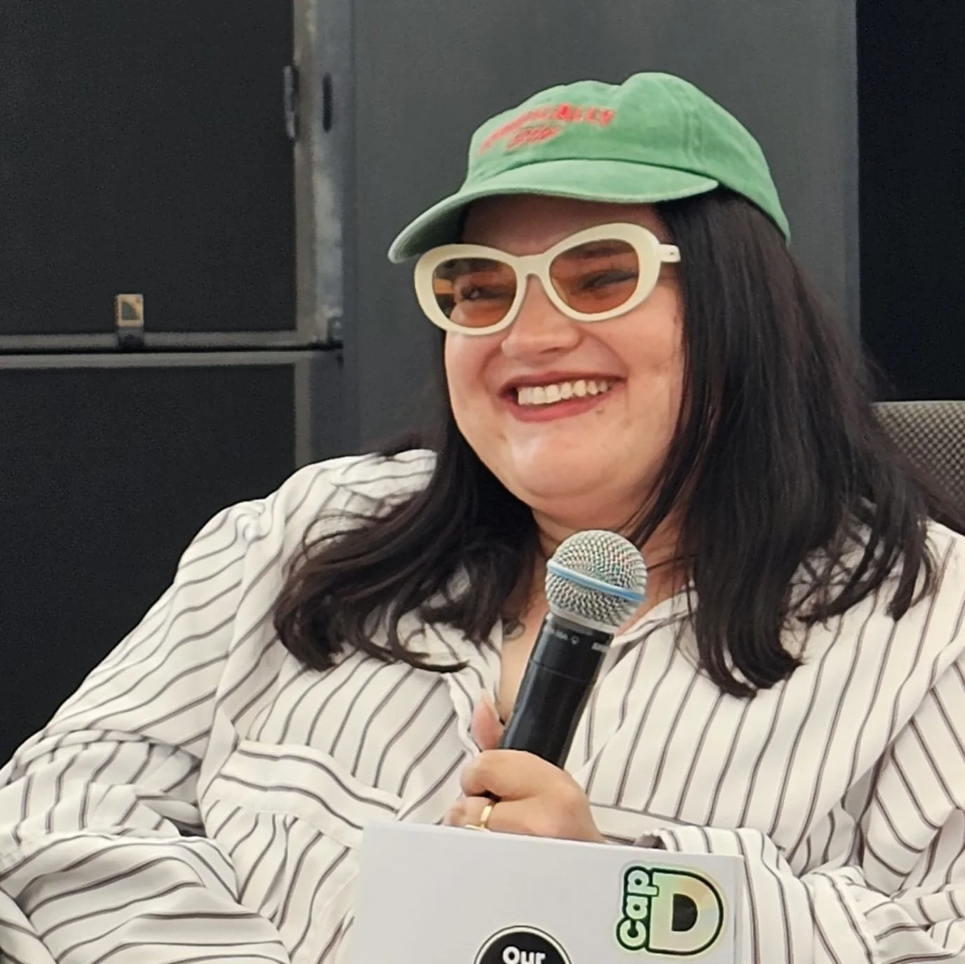 Kelly smiling, holding a microphone