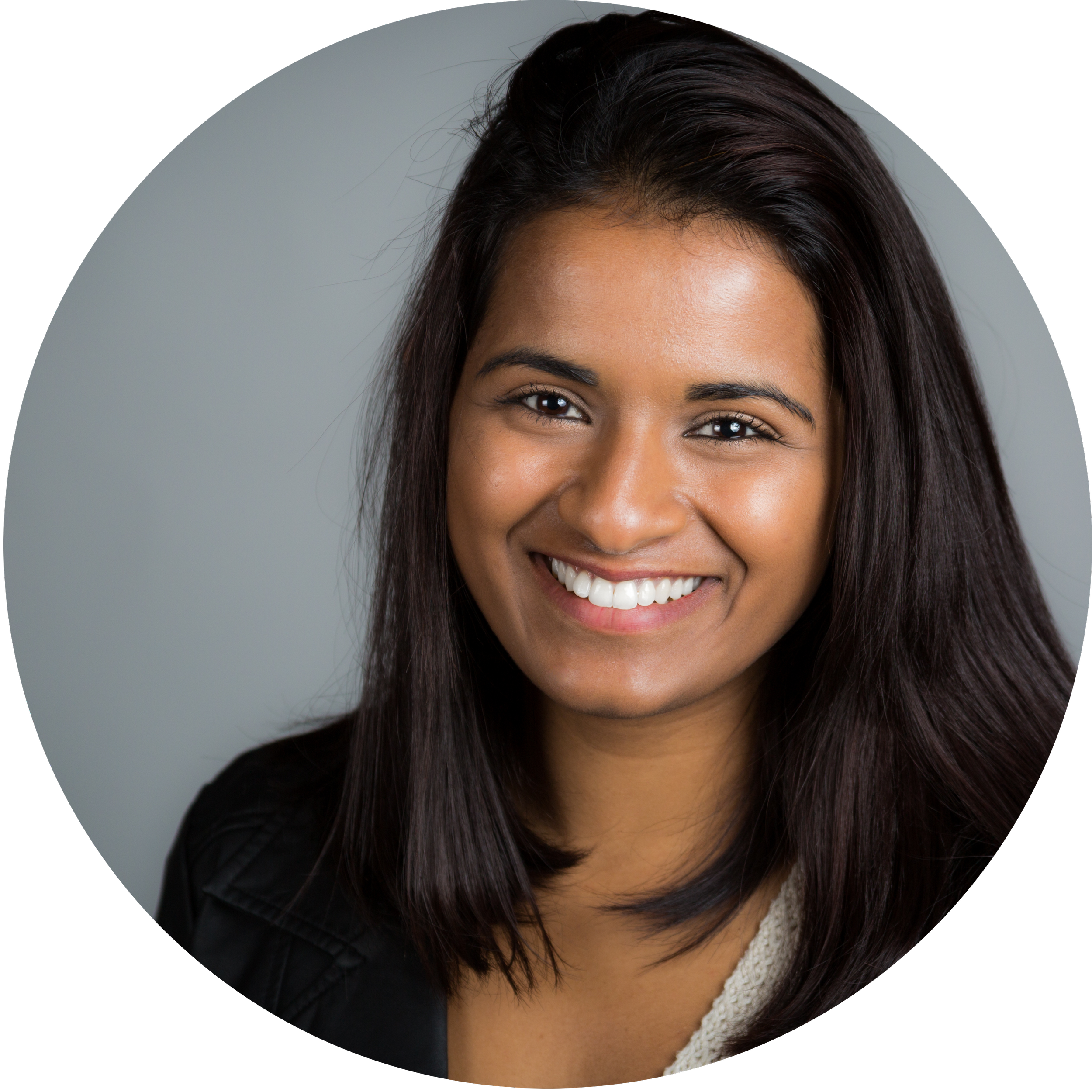 Smiling woman with long dark hair, wearing a black jacket and beige top, against a light gray background.