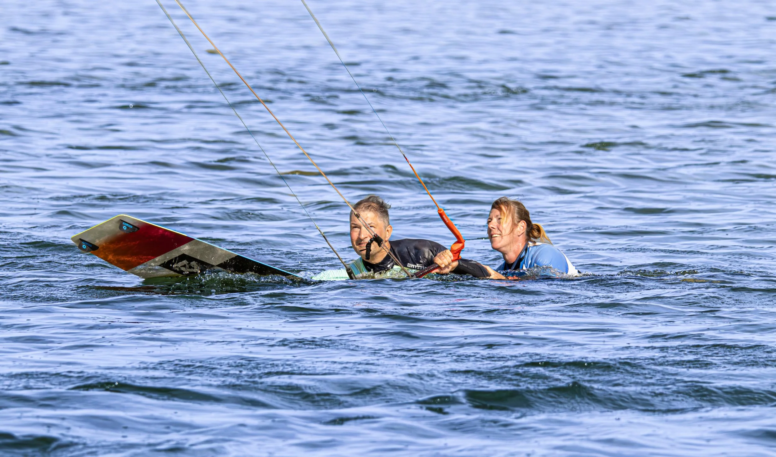 Twee mensen die hulp krijgen bij het uit het water halen van een beschadigd skateboard.