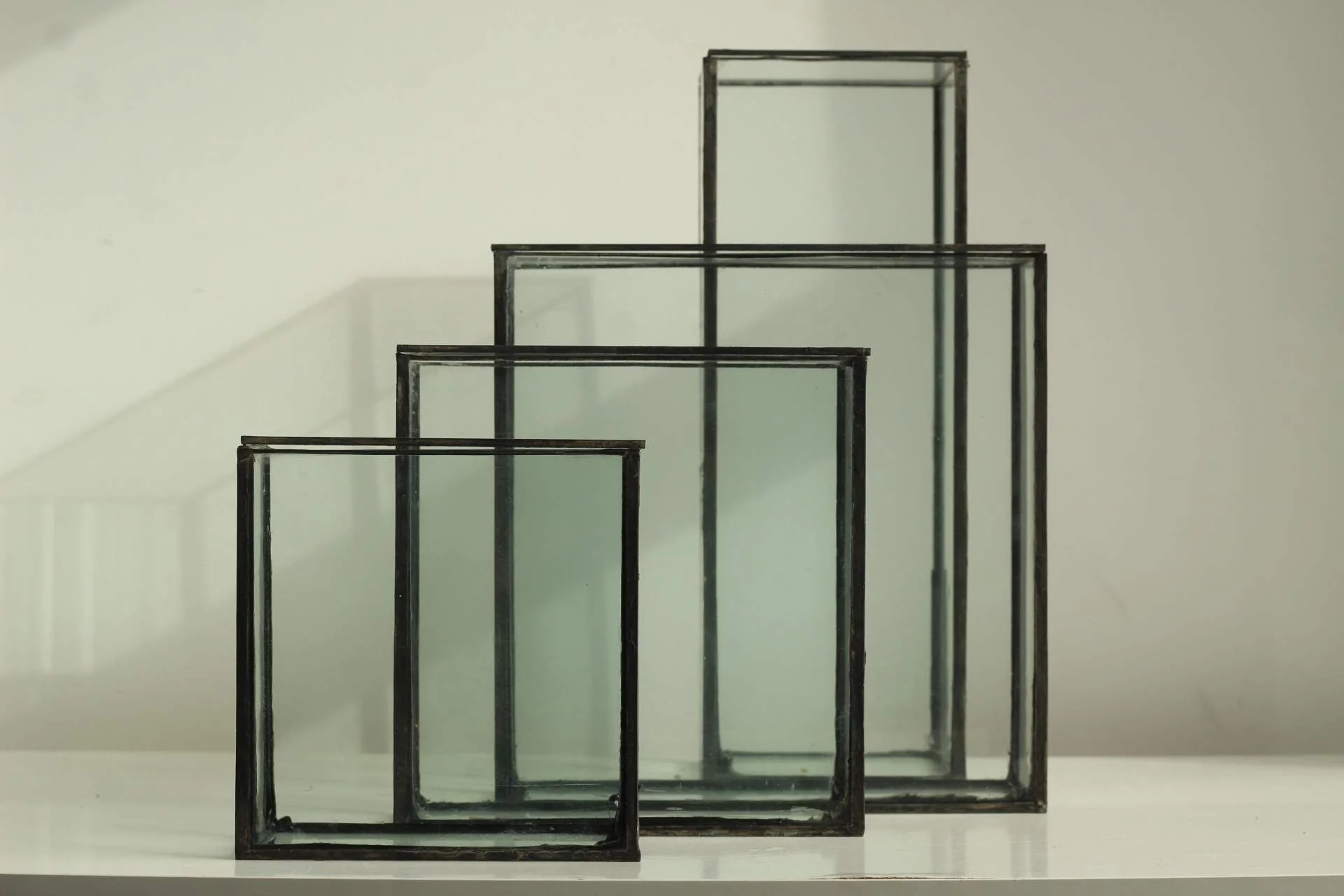 Set of four square glass frames of varying sizes, arranged on a white surface against a plain background.