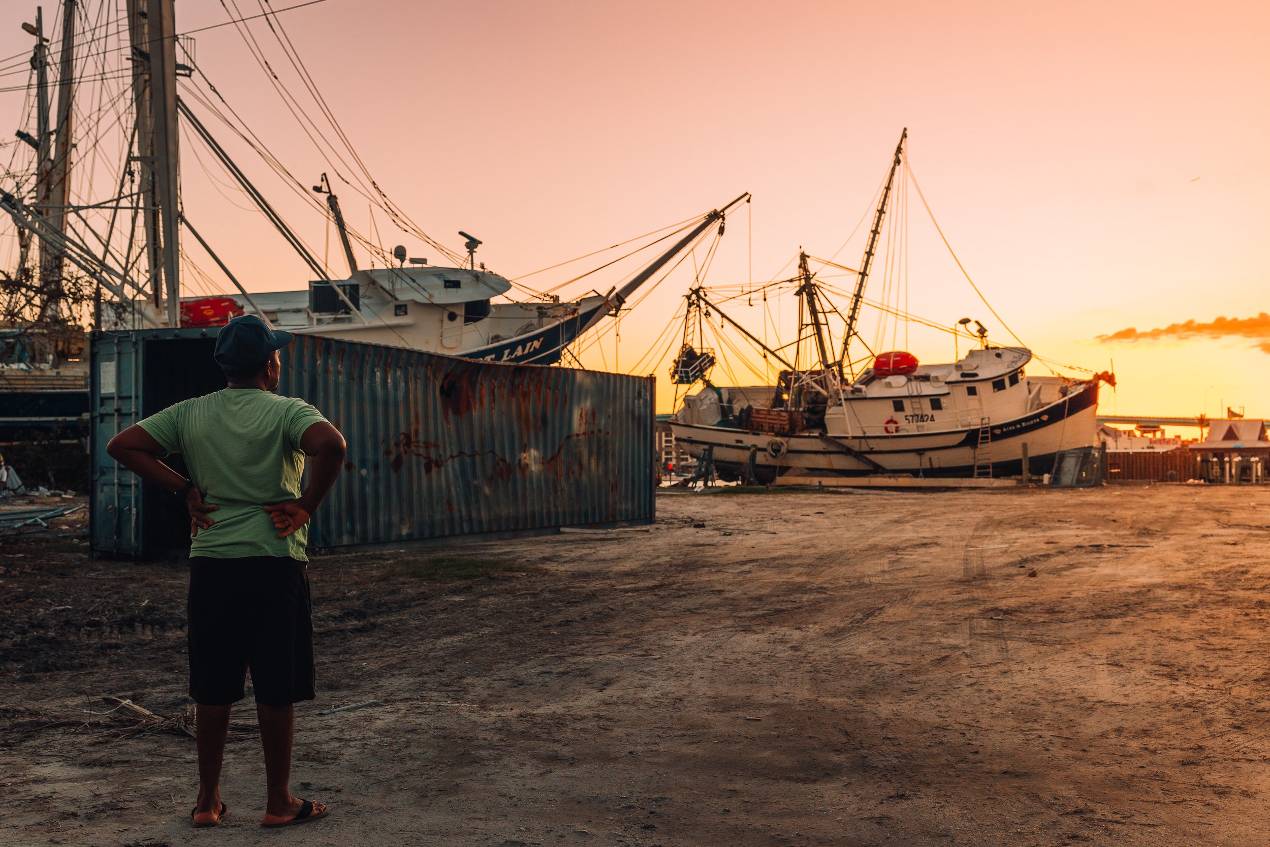 man looking shrimping boats on the land after Hurricane Ian damage in Fort Lauderdale, Florida