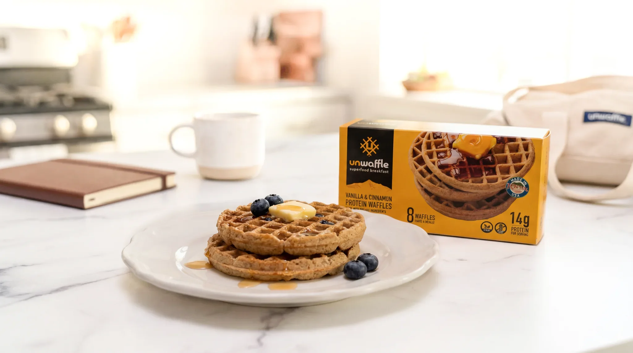 Plate of waffles topped with fruit beside a mug and a box of Unwaffle waffles on a kitchen counter, representing a simple and nourishing breakfast option for busy mornings.