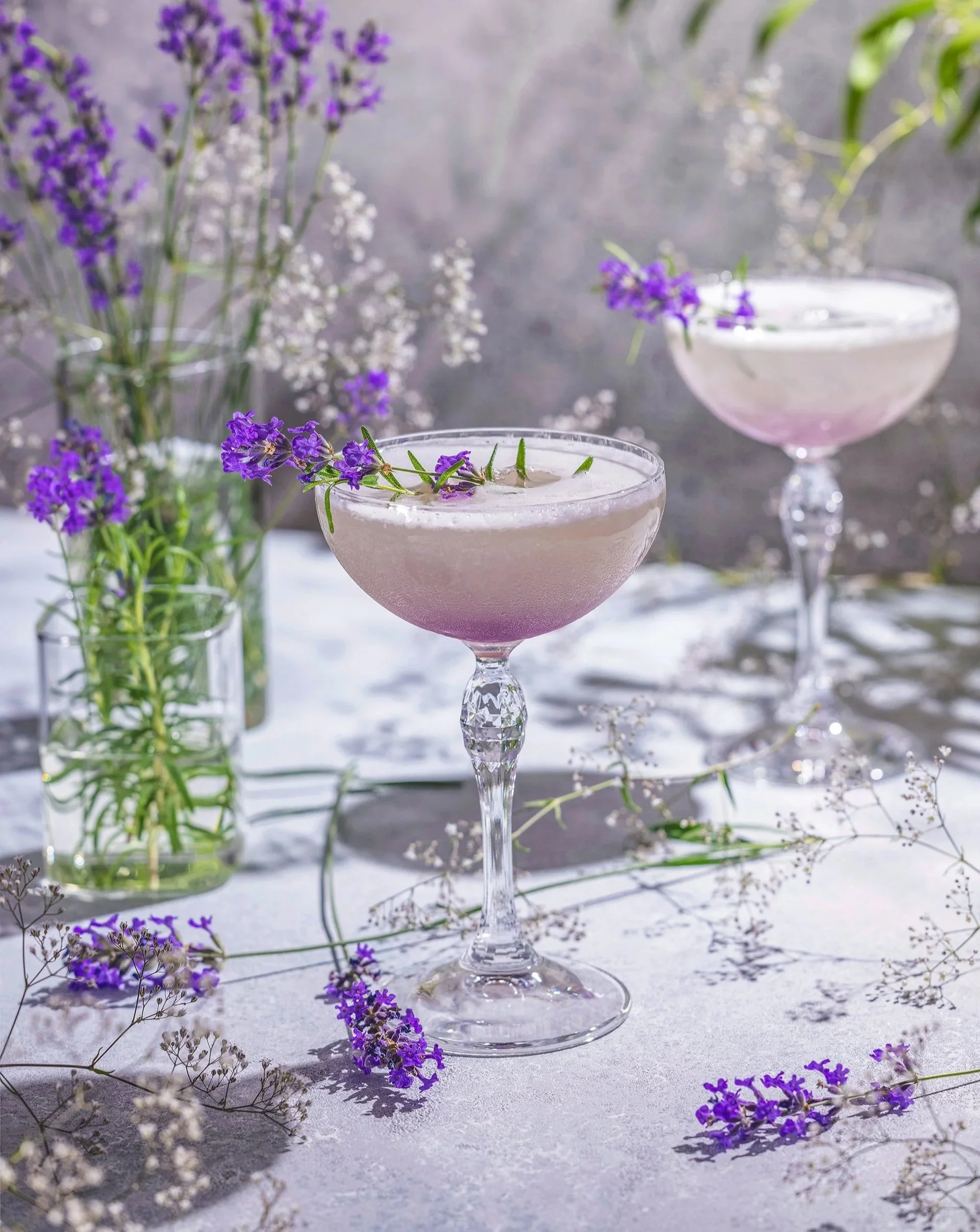 Elegant floral cocktail with a soft lavender hue, garnished with fresh lavender and herbs, served in a coupe glass. A refreshing, botanical-inspired drink perfect for spring, brunch, or a refined dining experience