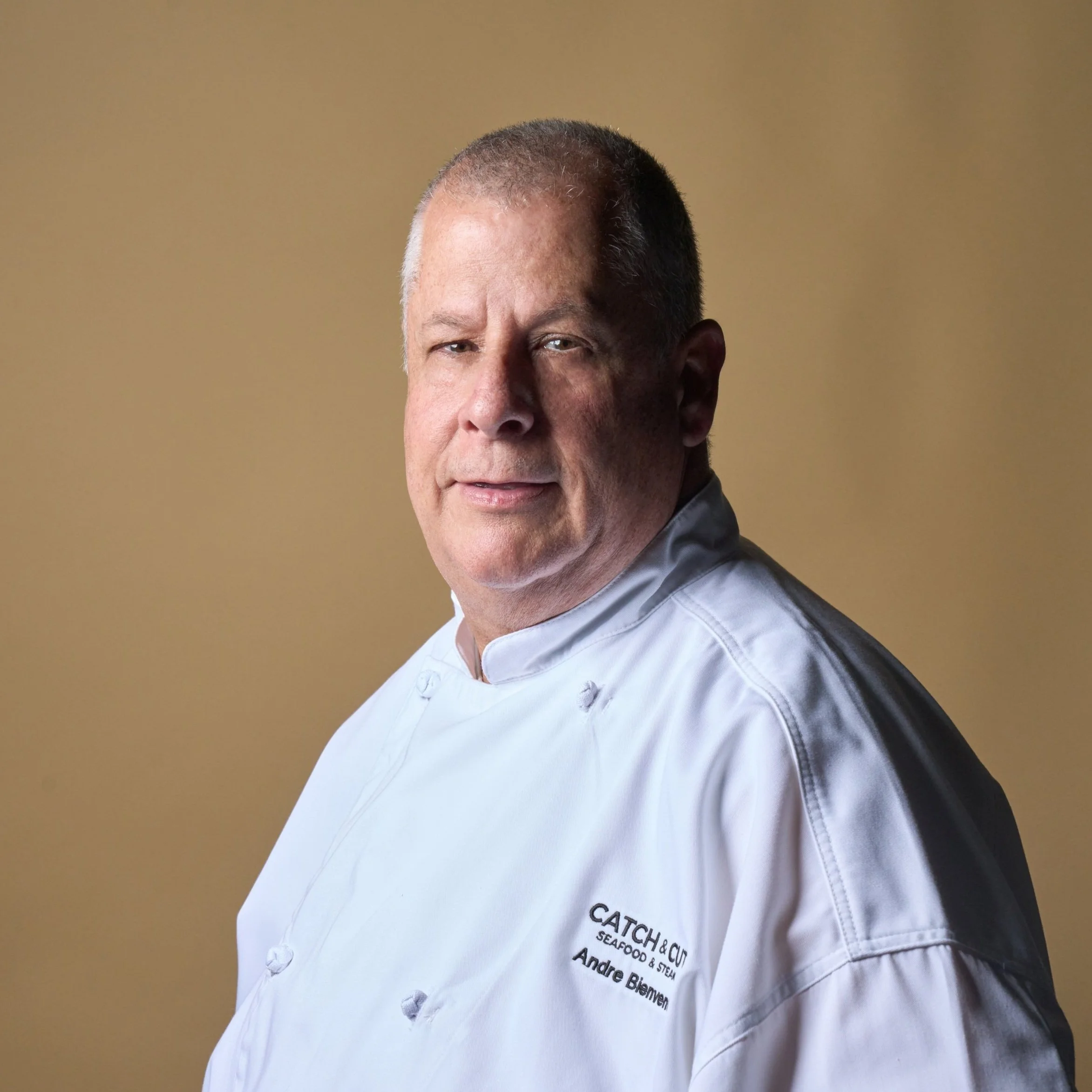 Partner & Executive Chef Andre Bienvenu in white jacket with embroidered name and logo.