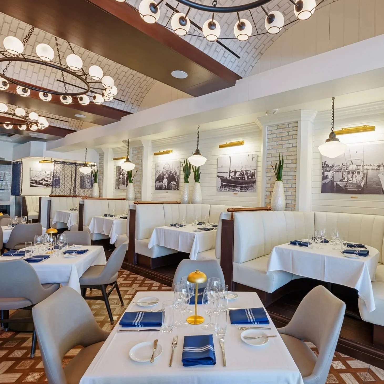 Main dining room at Catch & Cut Seafood & Steak in Fort Lauderdale featuring elegant booth seating, white tablecloths, modern lighting, and upscale coastal décor