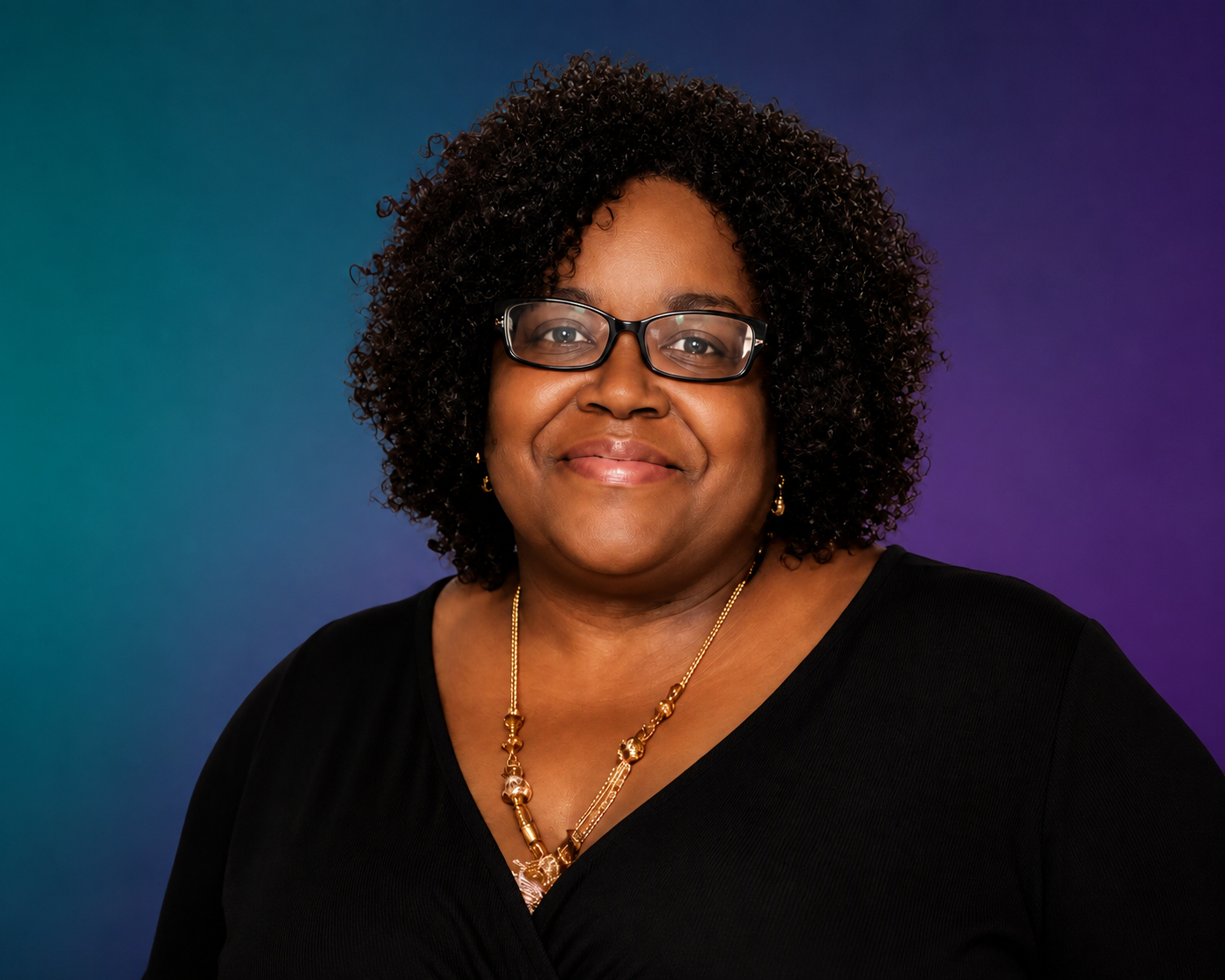 A woman with curly black hair, wearing glasses, gold jewelry, and a black top, smiling against a blue and purple gradient background.