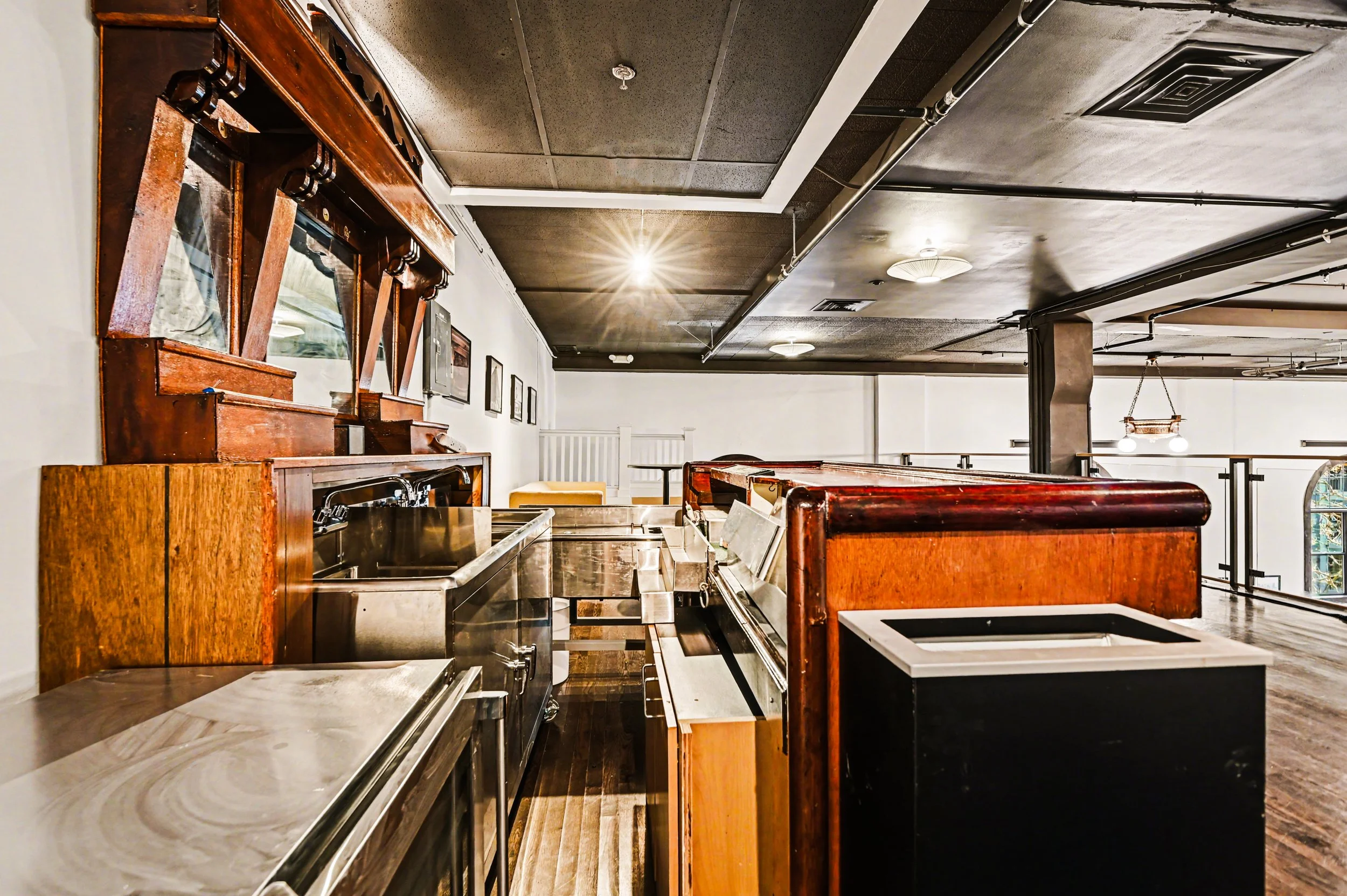 Nippon kan theatre, seattle, washington, event space, wedding,Interior of a vintage-style room with wooden furniture, stainless steel counters, framed pictures on the wall, and a dark ceiling with exposed pipes and ductwork.