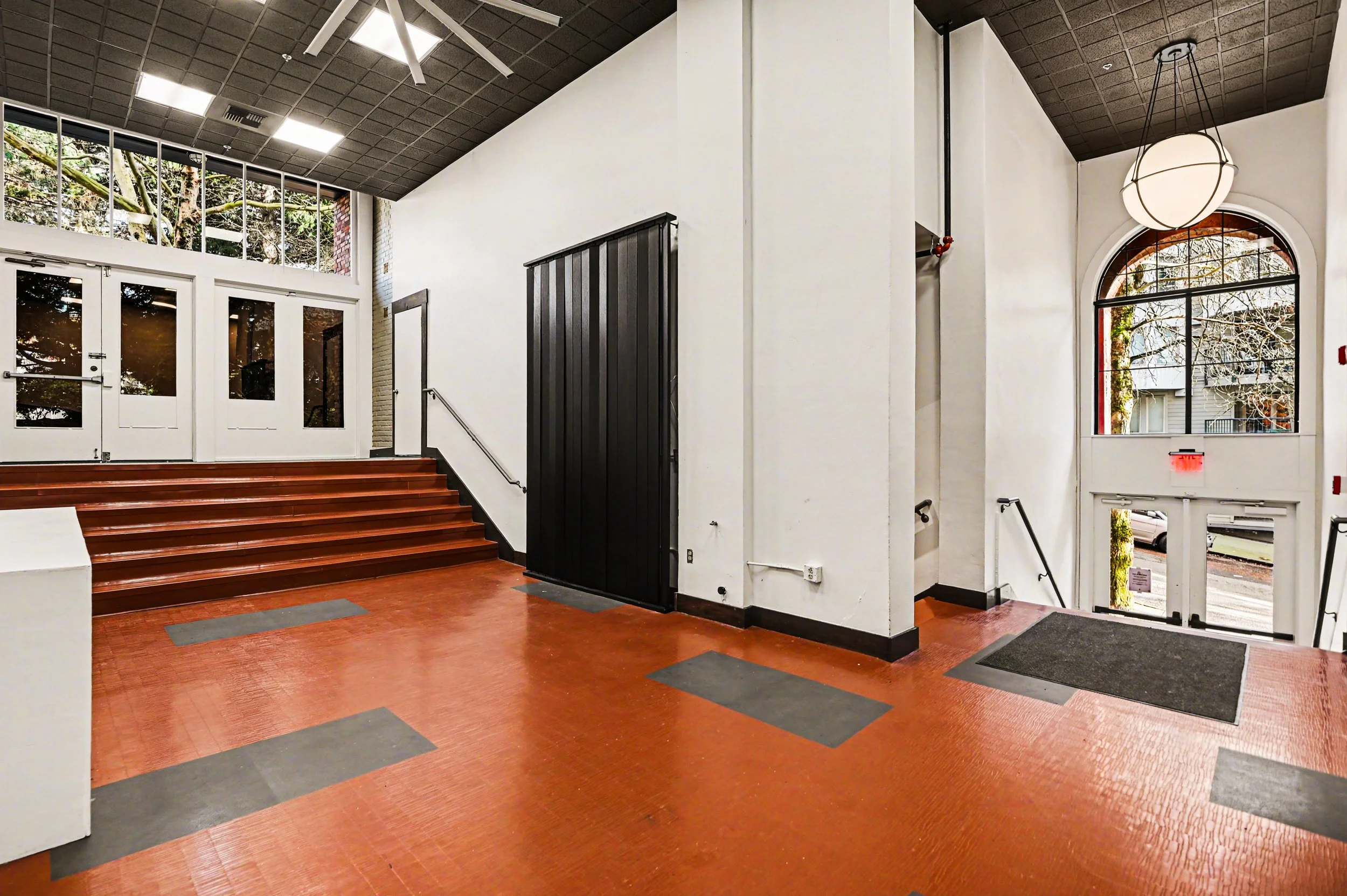 Nippon kan theatre, seattle, washington, event space, wedding, There are stairs leading up to double glass doors, and large windows letting in natural light. A hanging light fixture is visible near the entrance.