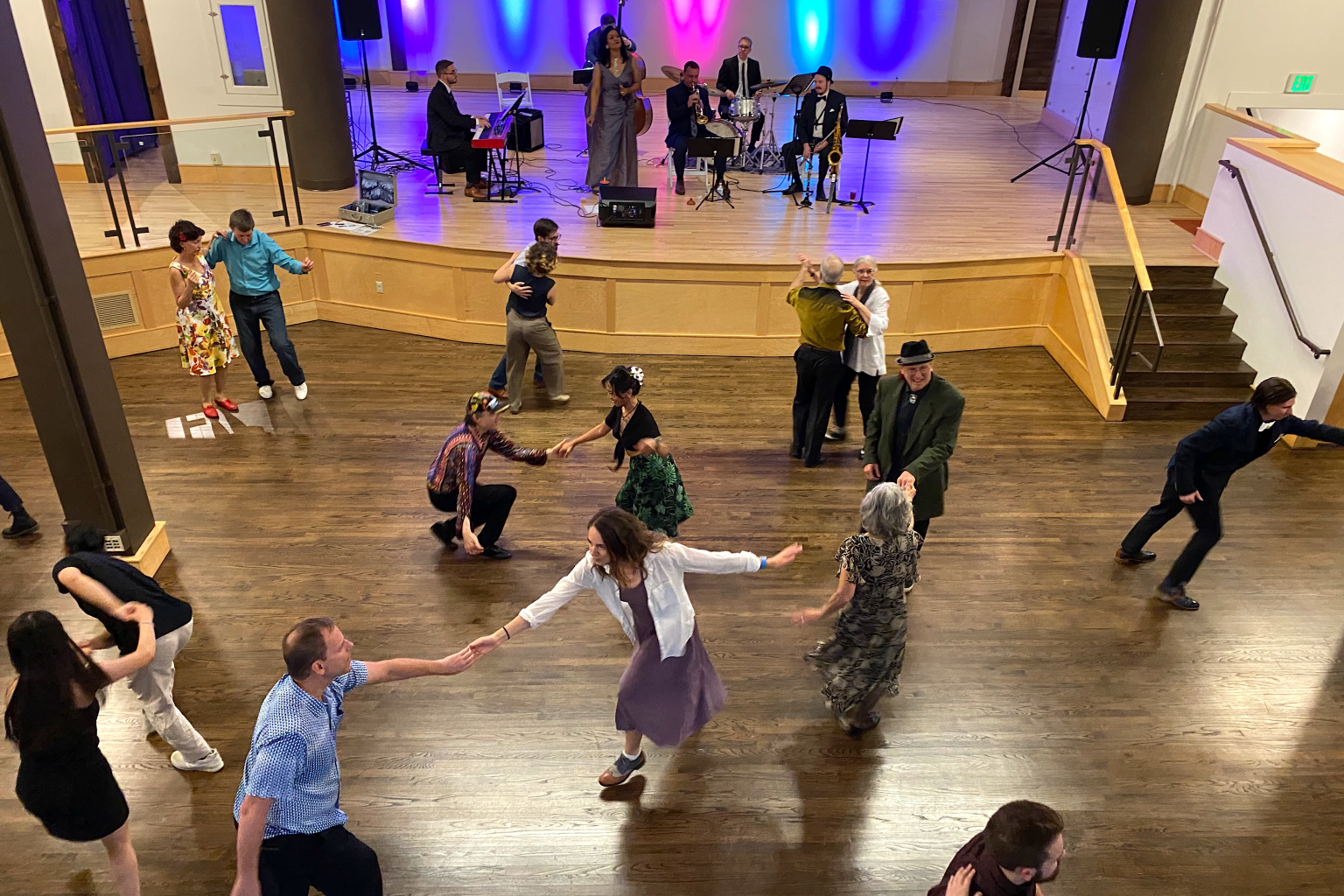 A backyard with a swimming pool, poolside lounge chairs, trees, and a modern house with outdoor seating area