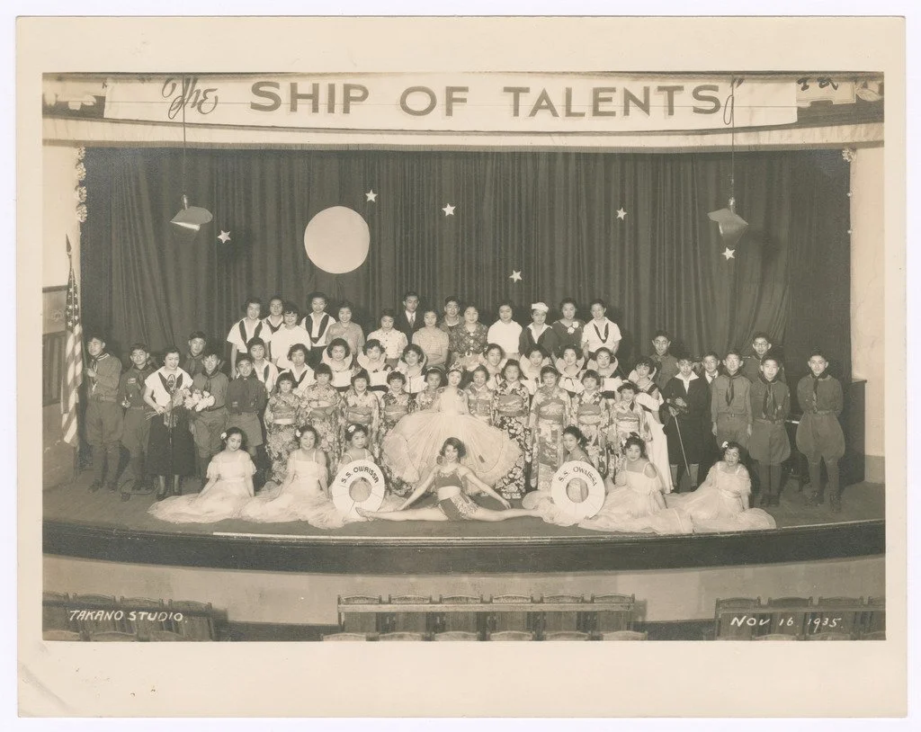 Black and white group photo of children and adults on stage at a talent show called 'The Ship of Talents,' taken at Takano Studio on November 16, 1935.