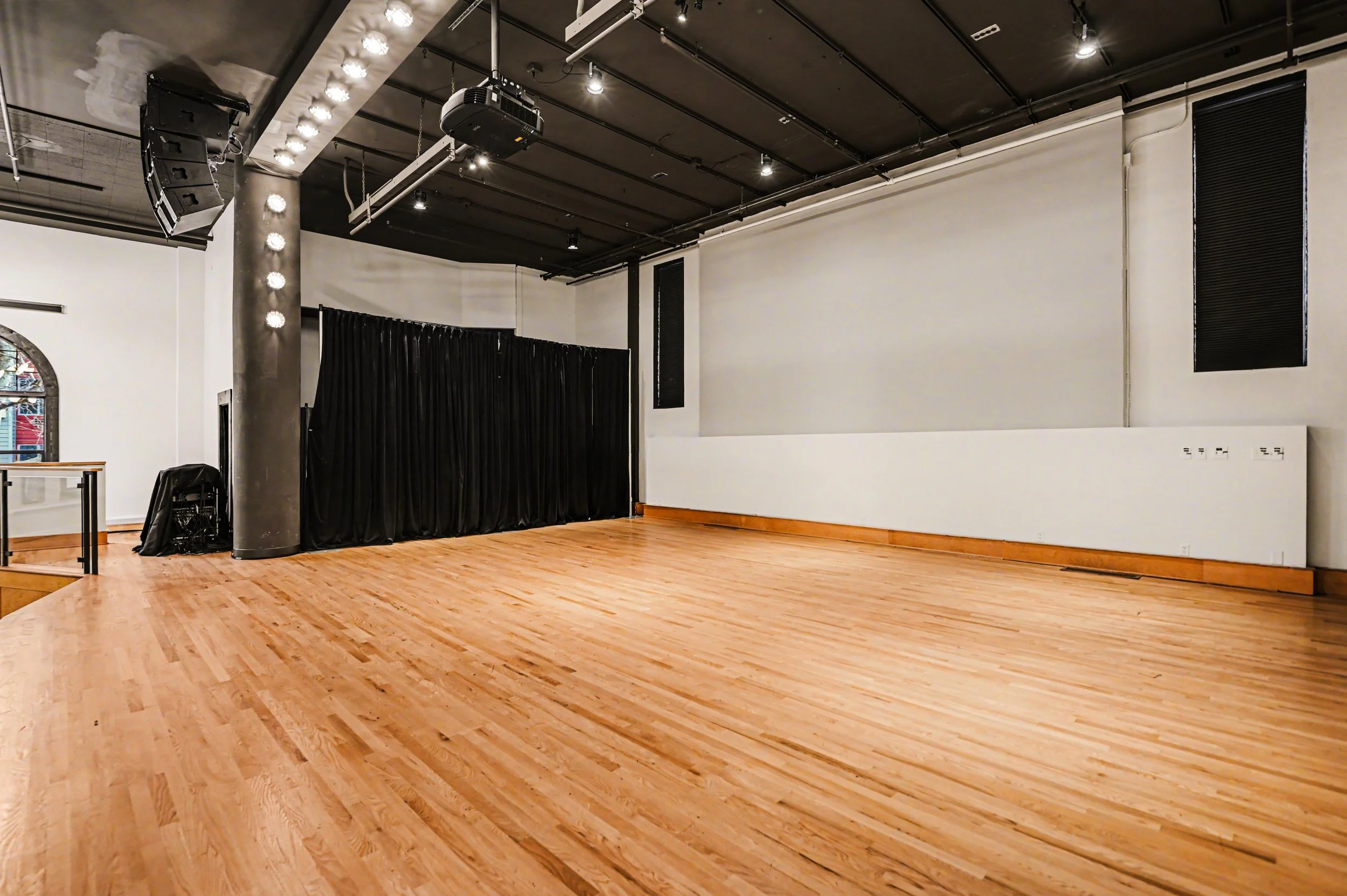 Nippon kan theatre, seattle, washington, event space, wedding,Empty room with wooden floor, black curtains, and equipment hanging from the ceiling, likely a dance or performance studio.
