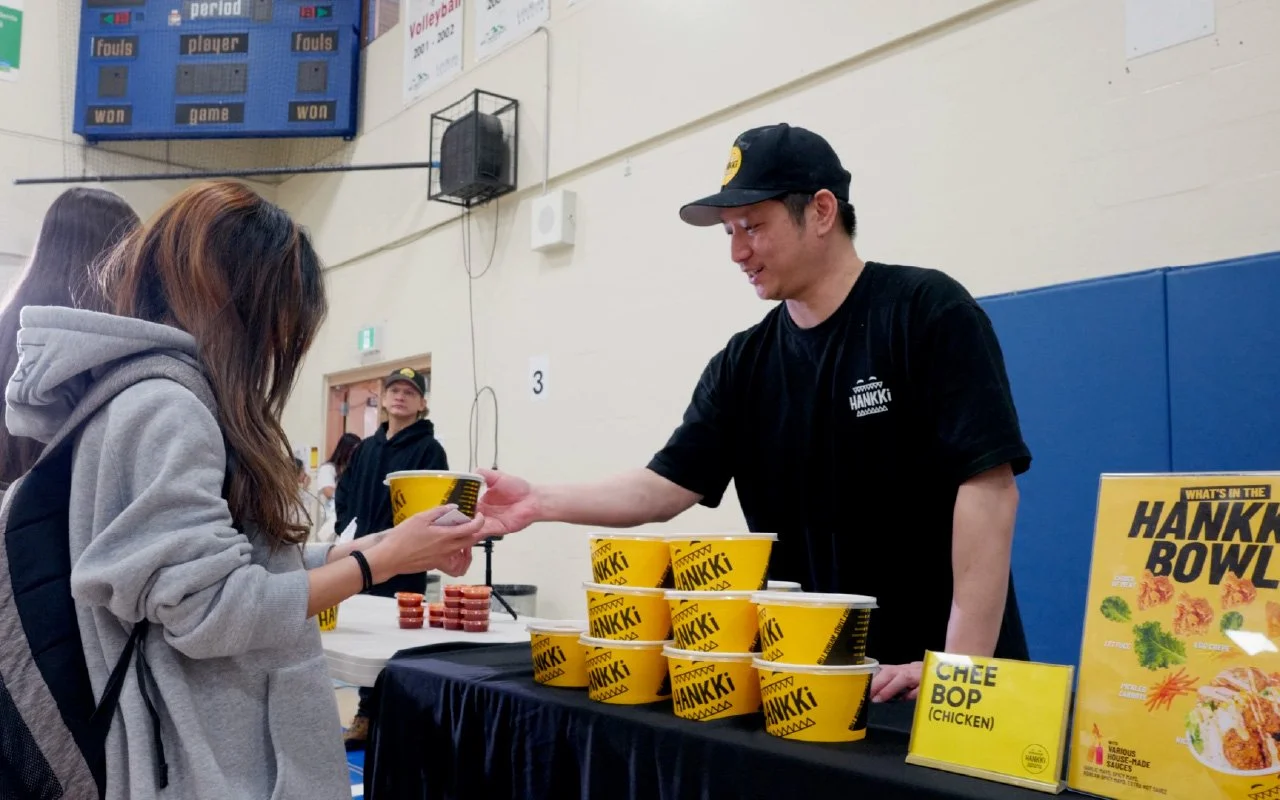 HANKKi team member serving a Korean BBQ Bowl to a student during the Father Lacombe High School event
