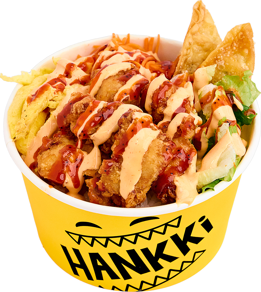A bowl of fried chicken pieces, lettuce, shredded cheese, and tortilla chips topped with creamy sauce and hot sauce in a yellow container with the word 'Hank's' and a cartoon face.