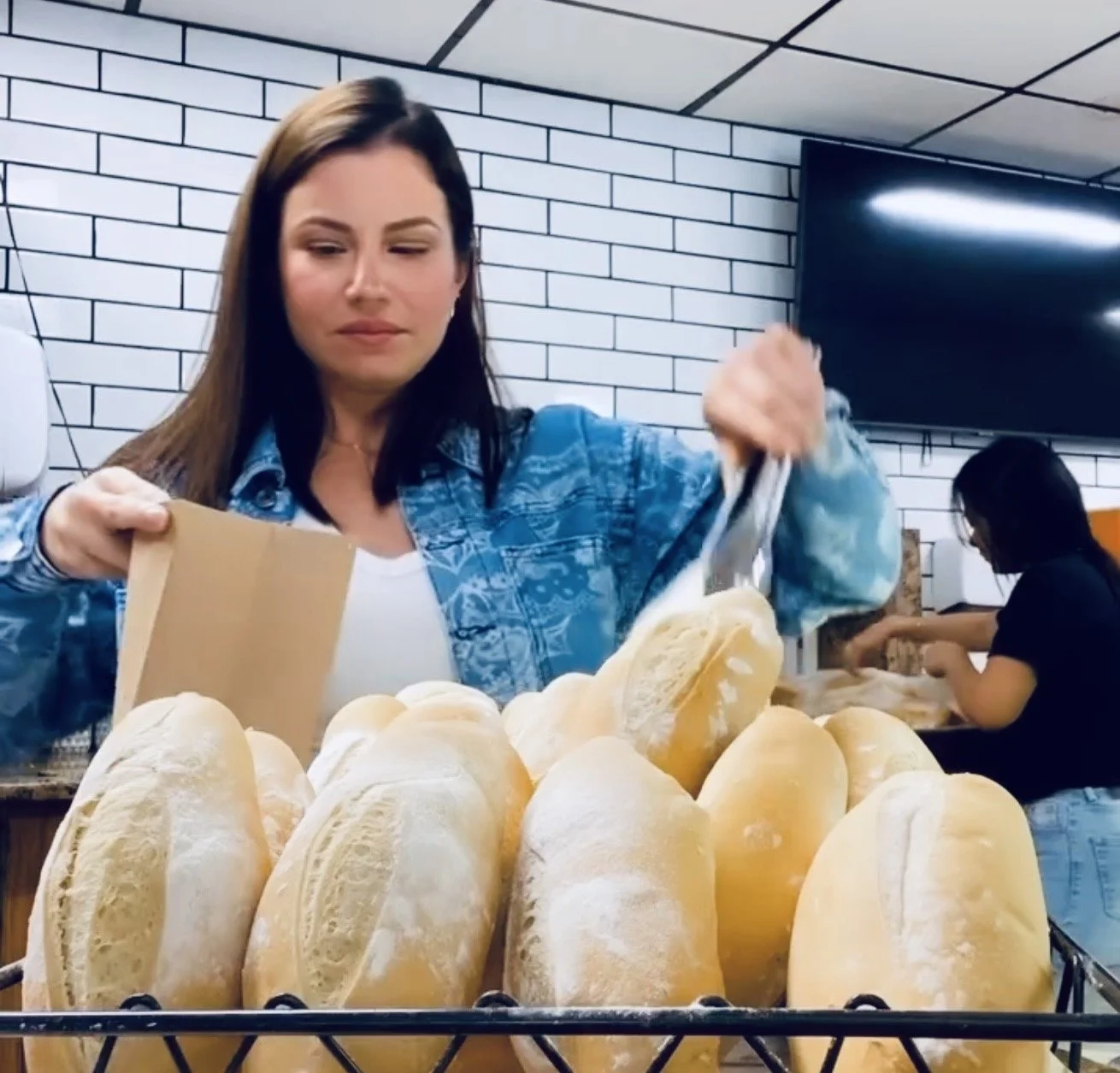 Woman selecting bread loaves in a bakery