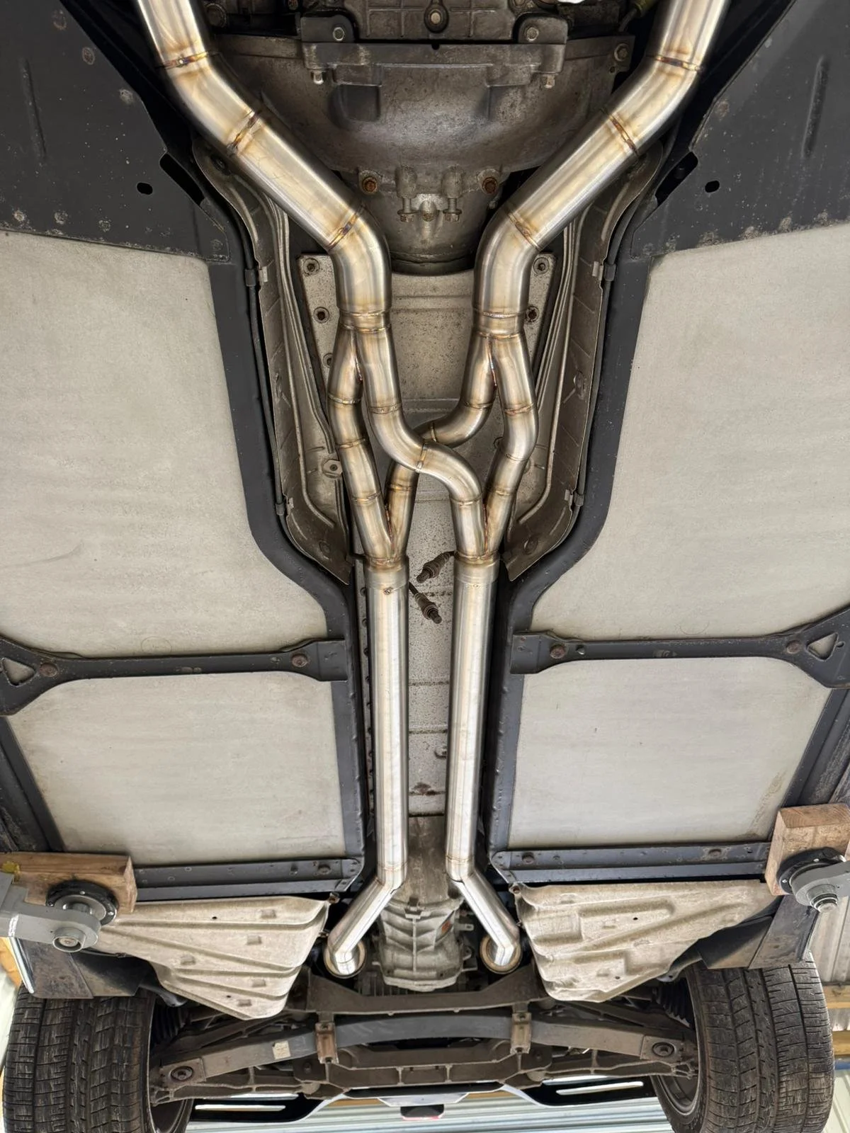 Underneath view of a vehicle highlighting custom exhaust pipes and undercarriage.