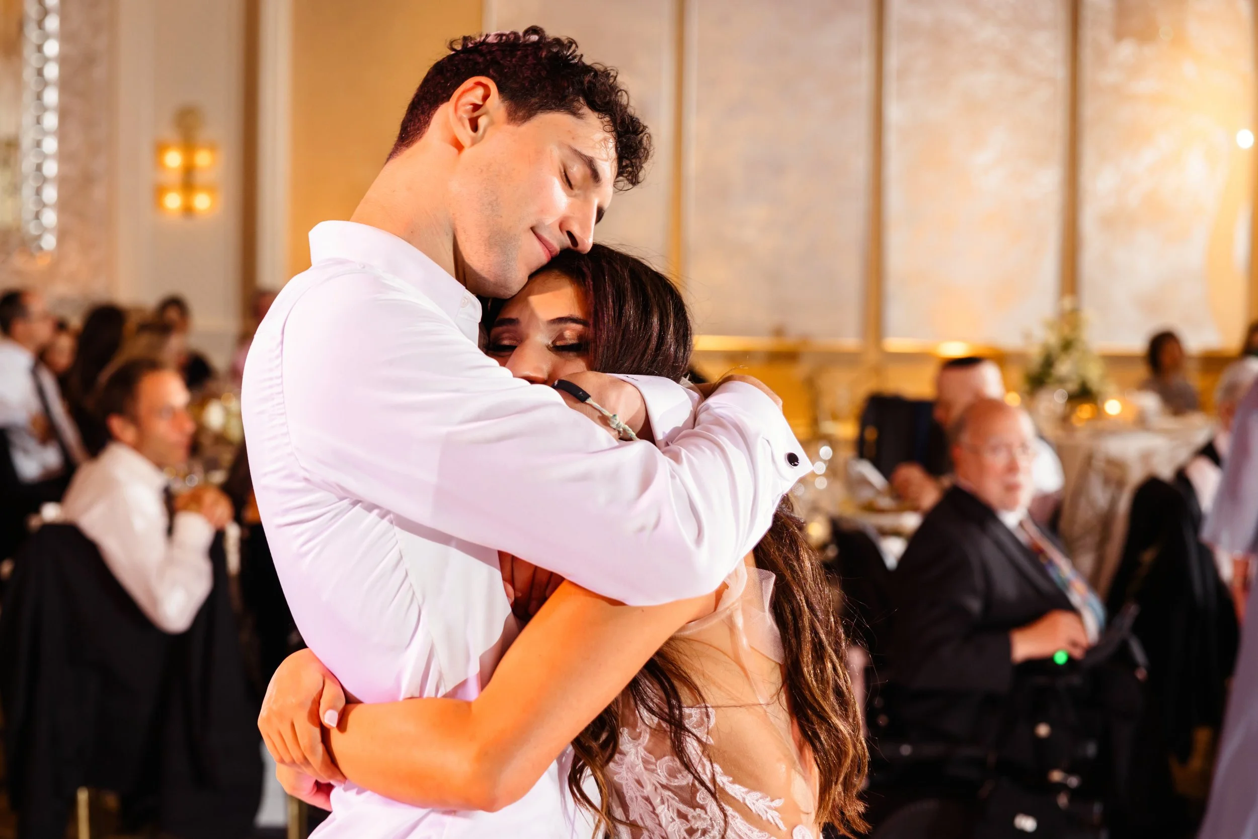 Newlyweds sharing an emotional embrace on the dance floor at their wedding reception, the moment a planner frees hosts to enjoy