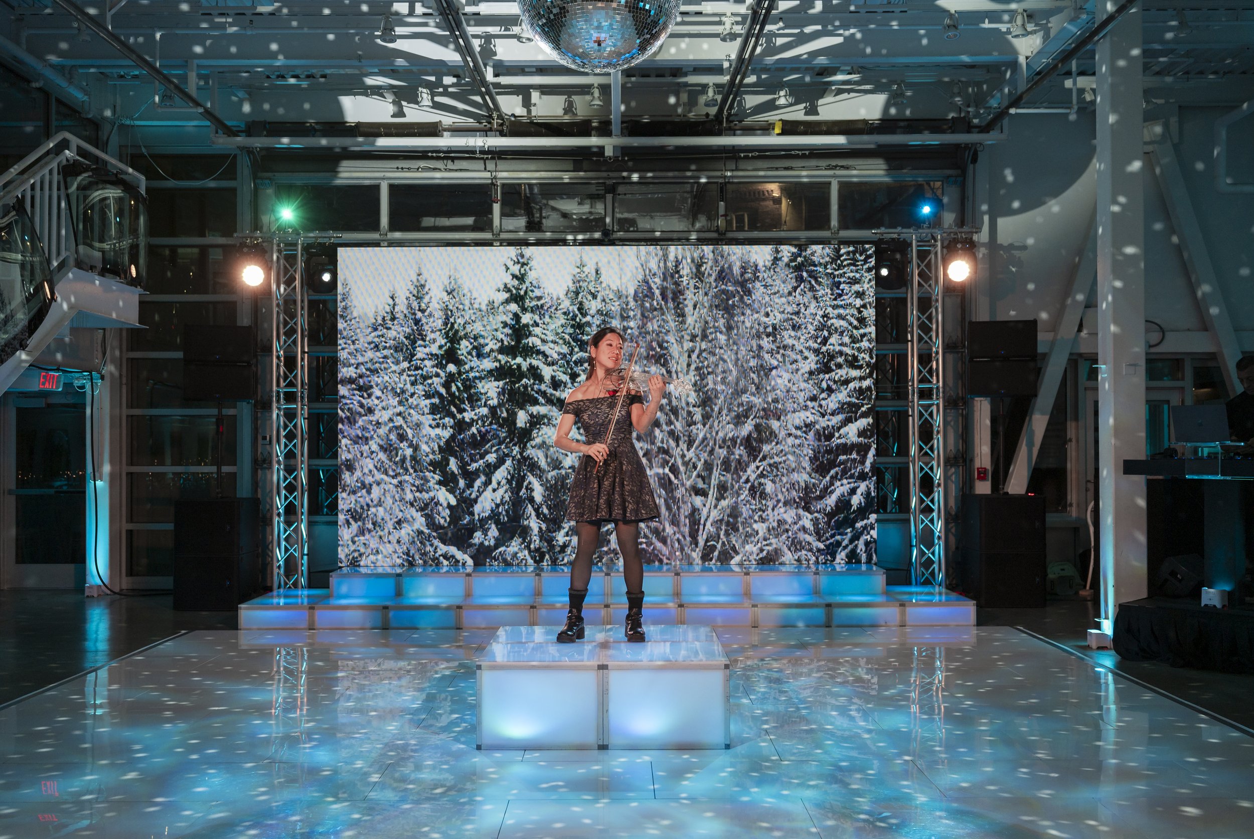 LED video wall showing a snowy forest behind the dance floor at a Boston winter holiday party at Artists For Humanity, produced by Siagel Productions