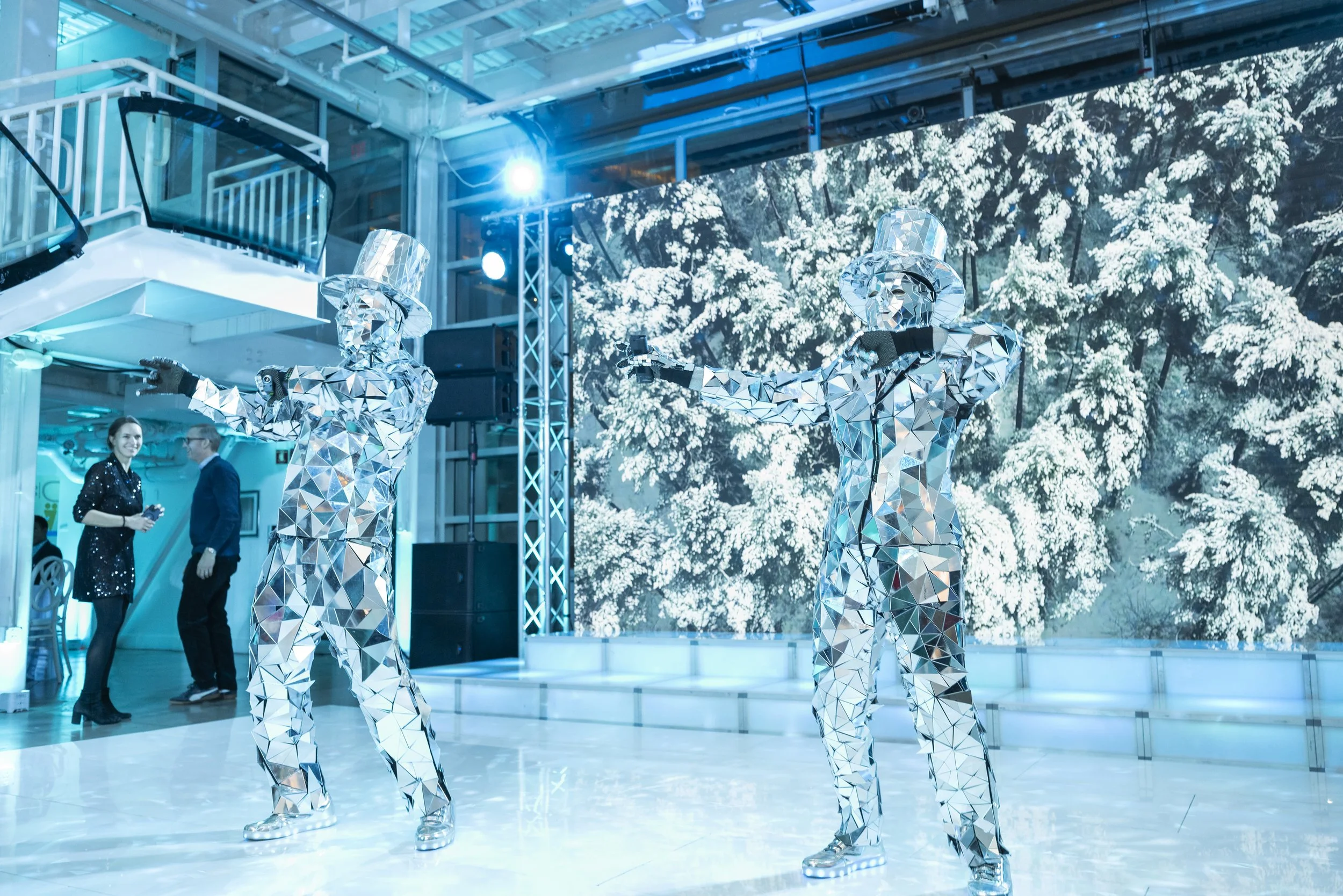 Mirror Men roaming performers dancing with guests in front of a snowy LED wall at a Boston winter holiday party by Siagel Productions