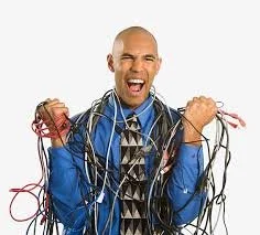 A man in a blue shirt and tie, smiling and shouting, holding tangled wires in both hands against a white background.