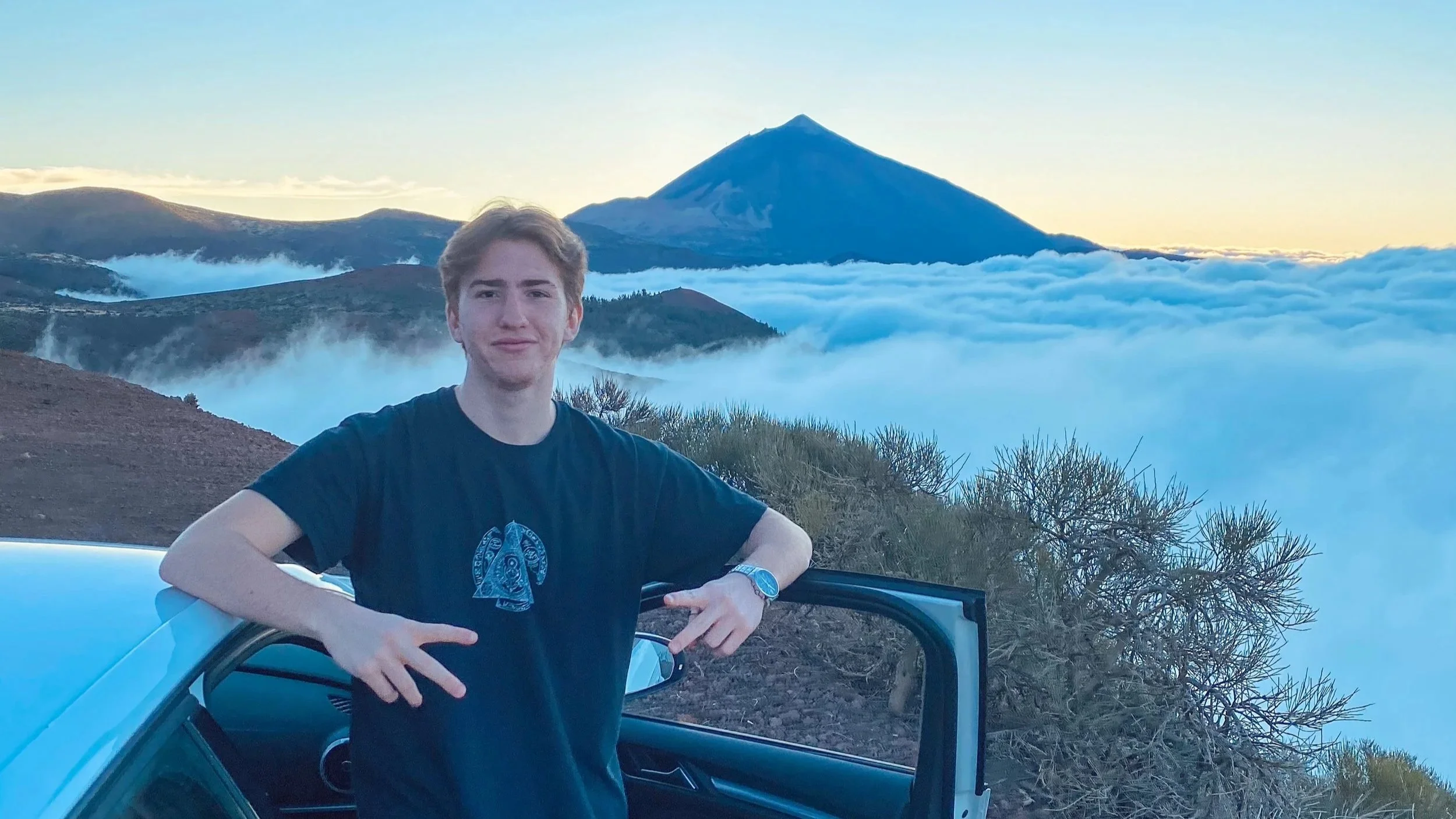 Max with a car rental and views of Mount Teide above the clouds above