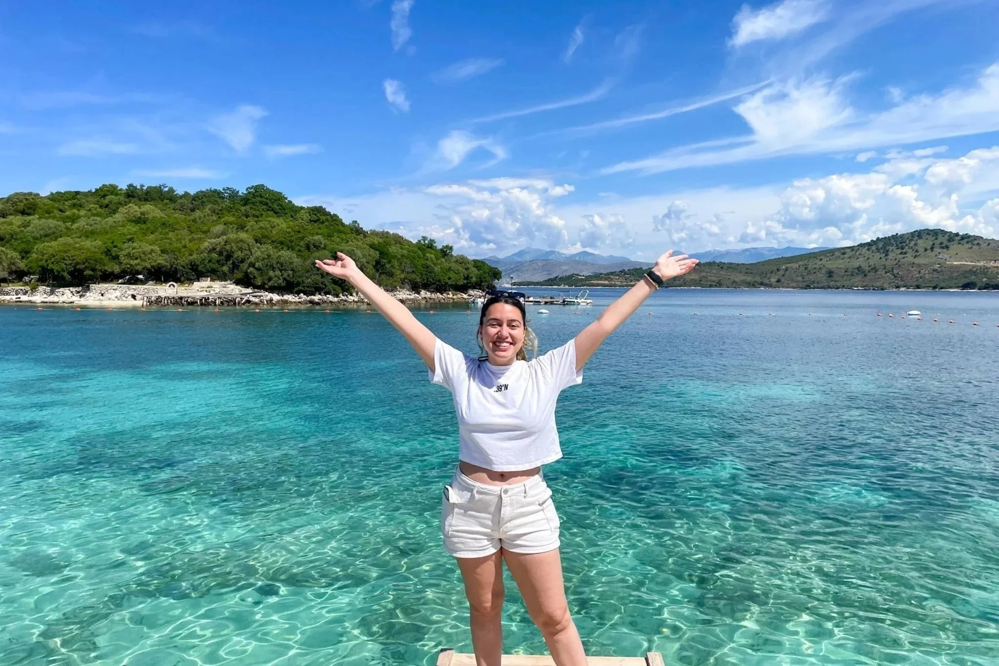 Carol arms open surrounded by crystal clear waters in Ksamil, Albania
