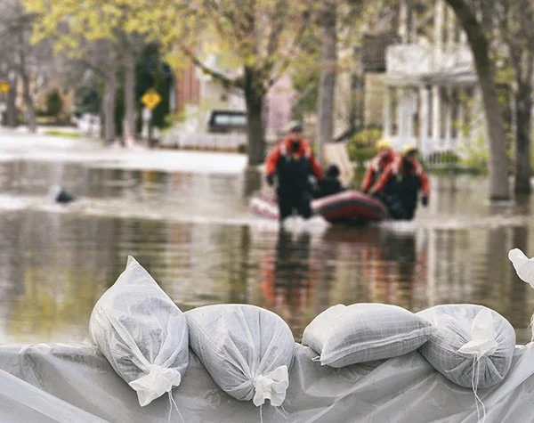 Sand bags holding back flood waters with water rescue crew in background