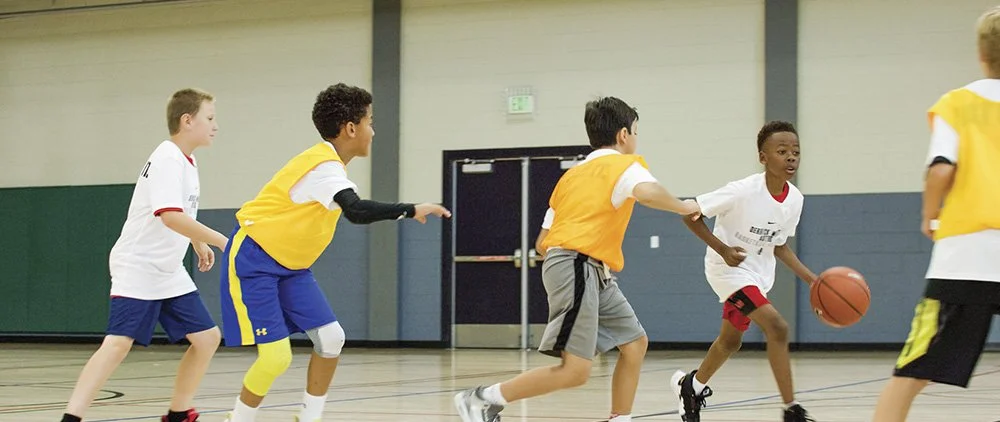 5 boys playing basketball inside a gym