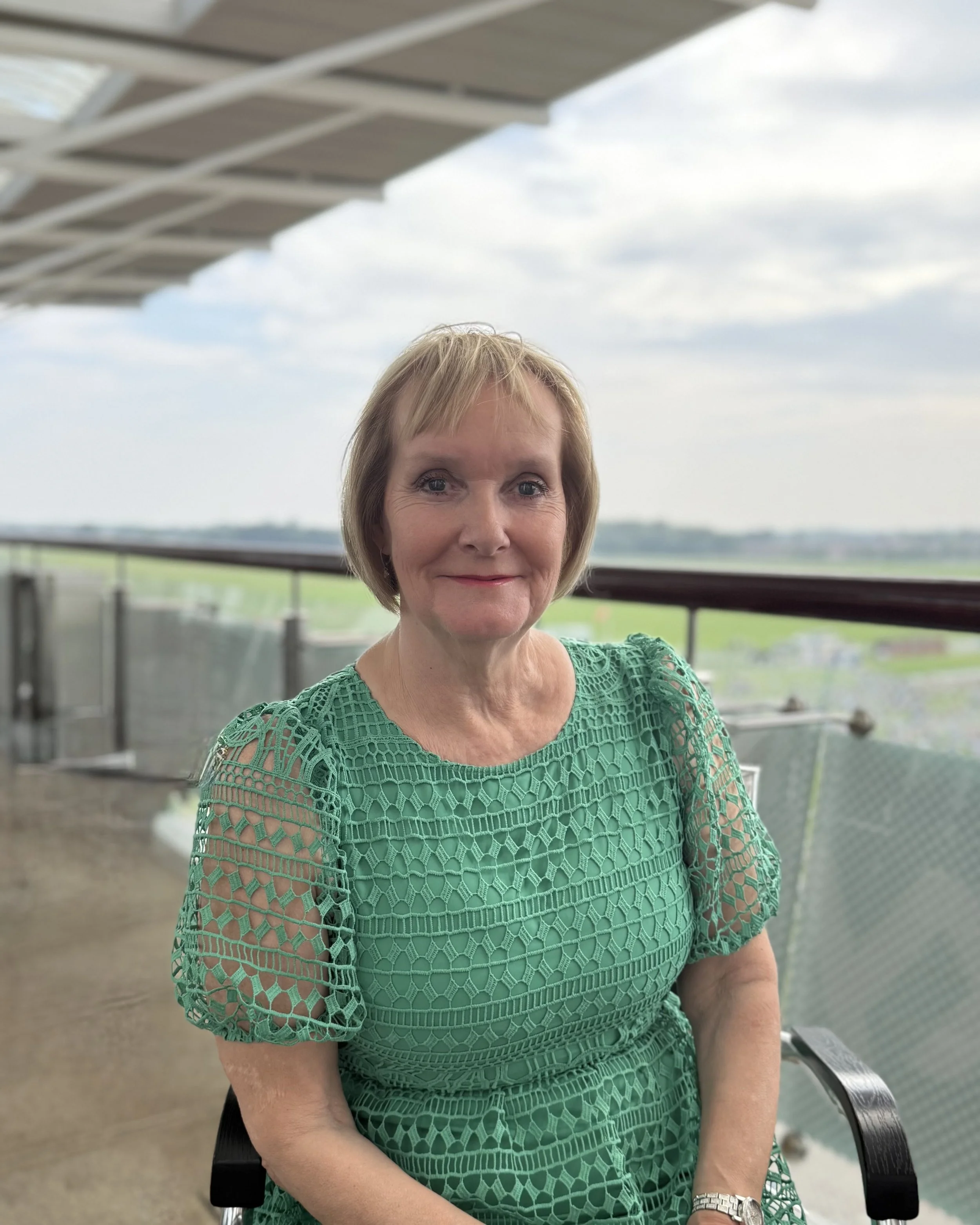 Female with short blonde hair, wearing a floral black and white top