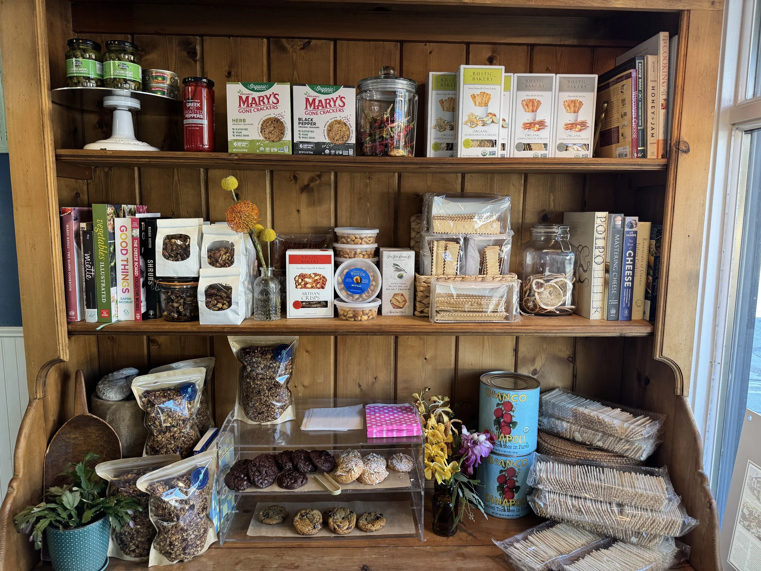 inside of siren sisters kitchen store. wooden retail shelf containing our cookies, nuts, granolas, crackers, etc...

