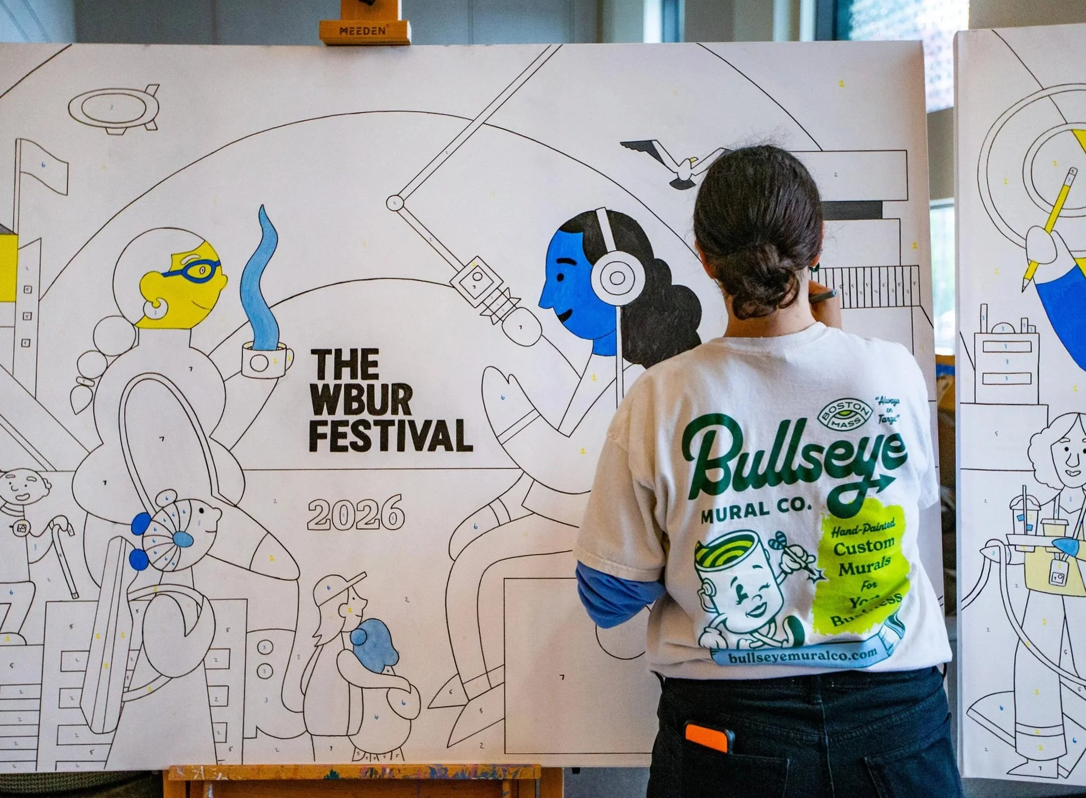 Bullseye muralist uses a paint markers on a large canvas color by numbers panel mural for The WBUR Festival at Boston University