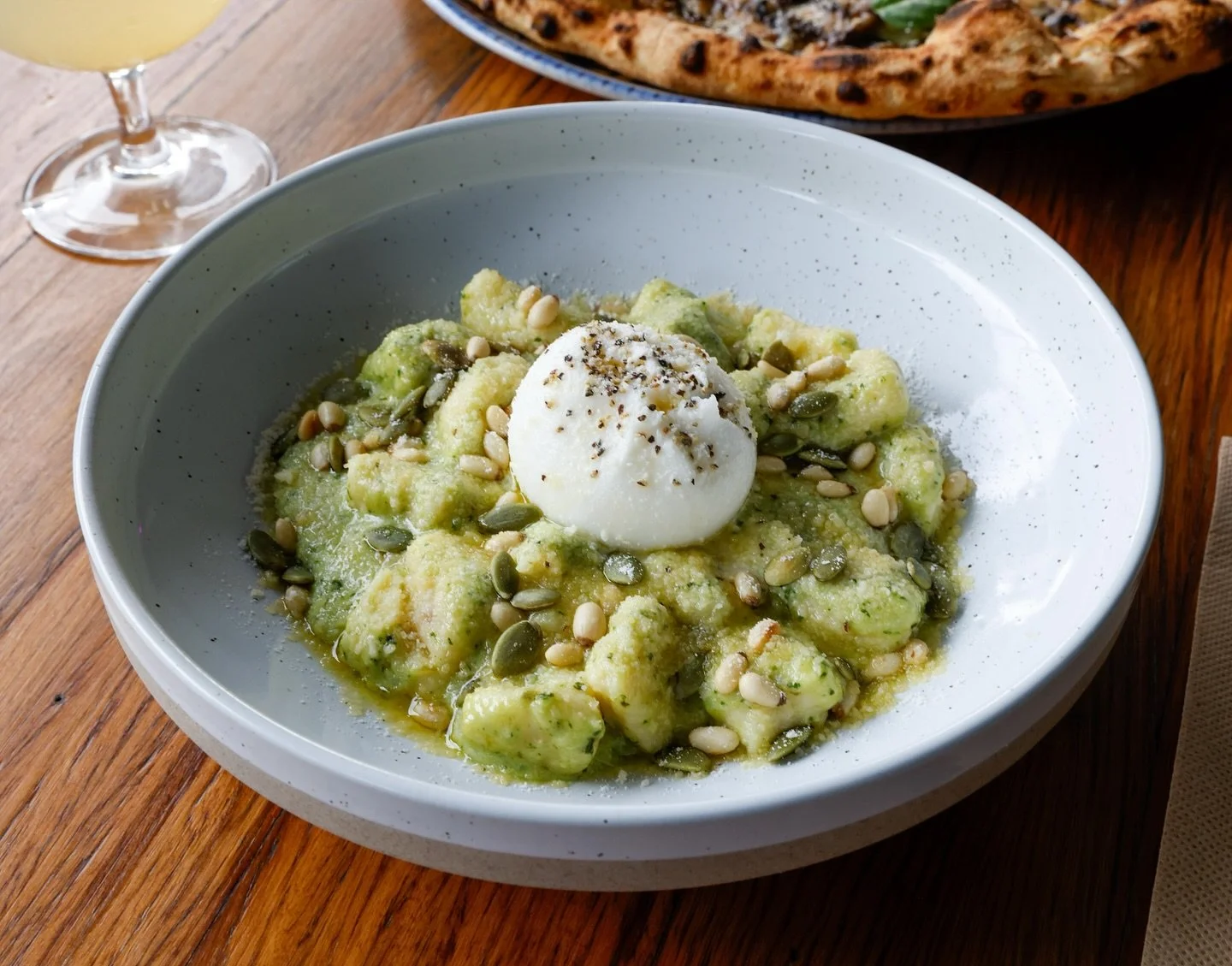 GNOCCHI PESTO E BURRATA 
Soft gnocchi coated in creamy basil pesto &amp; parmesan, topped with fresh burrata, toasted pine nuts and crunchy pumpkin seeds. Pure comfort in every bite. 🤌✨

#LaPiazzetta #GnocchiLovers #PestoPasta #BurrataDreams #Italia