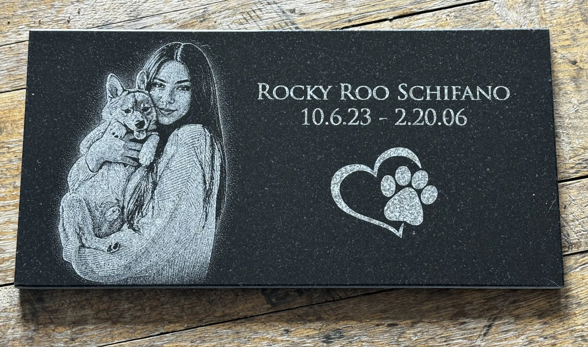 Rectangle granite engraved with woman holding her dog, the dog's name, dates of life and a heart with a dog paw.