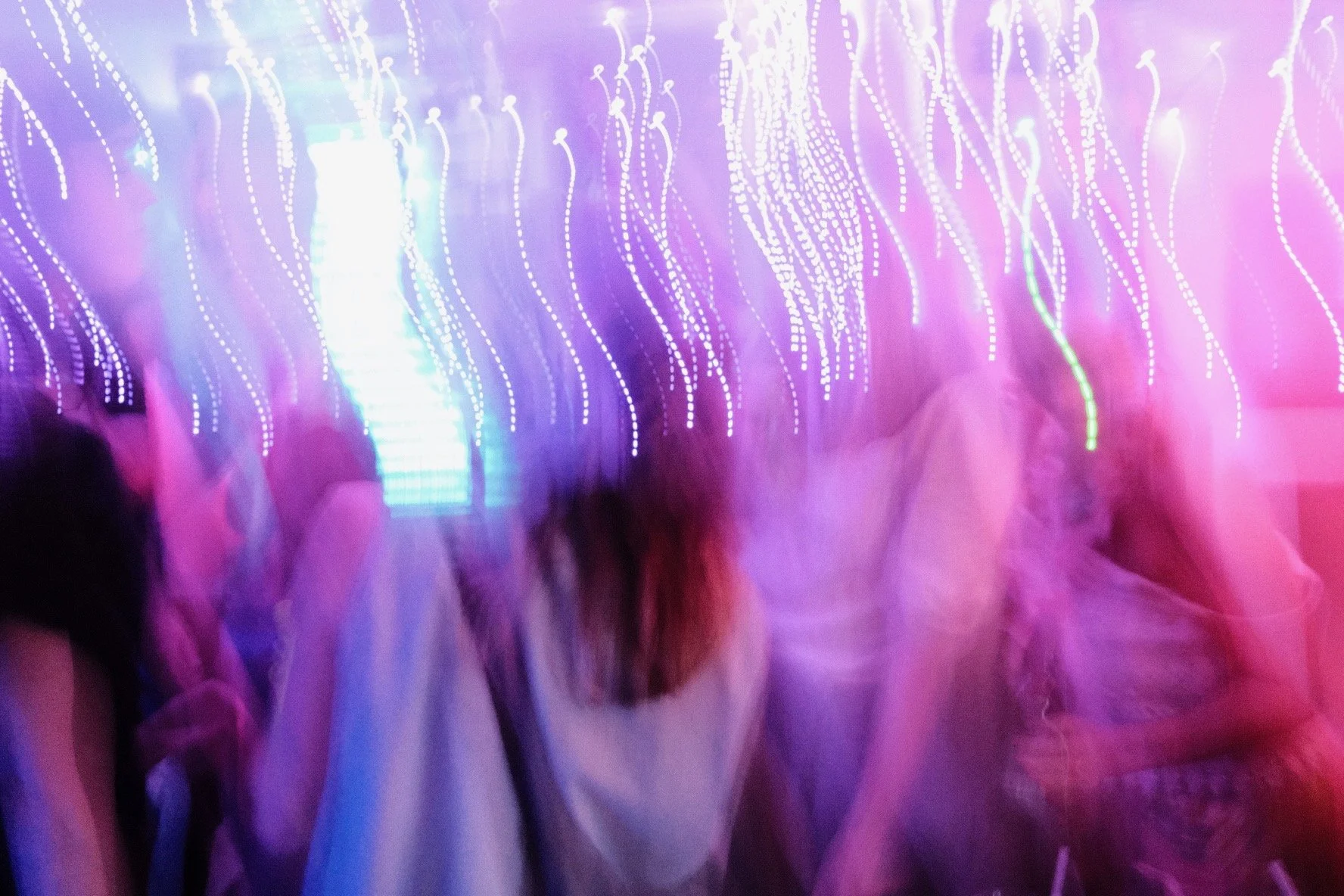 People at a vibrant party or event with colorful, blurred lights and decorations.