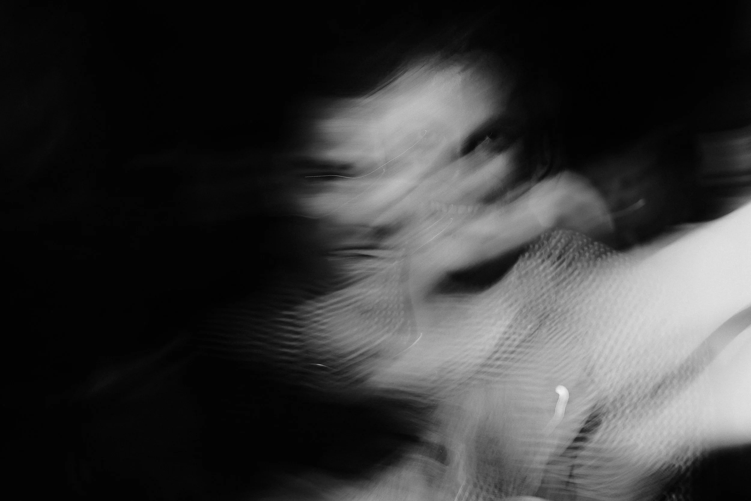 A black and white photo with blurred motion, possibly of a person's face or an abstract scene.
