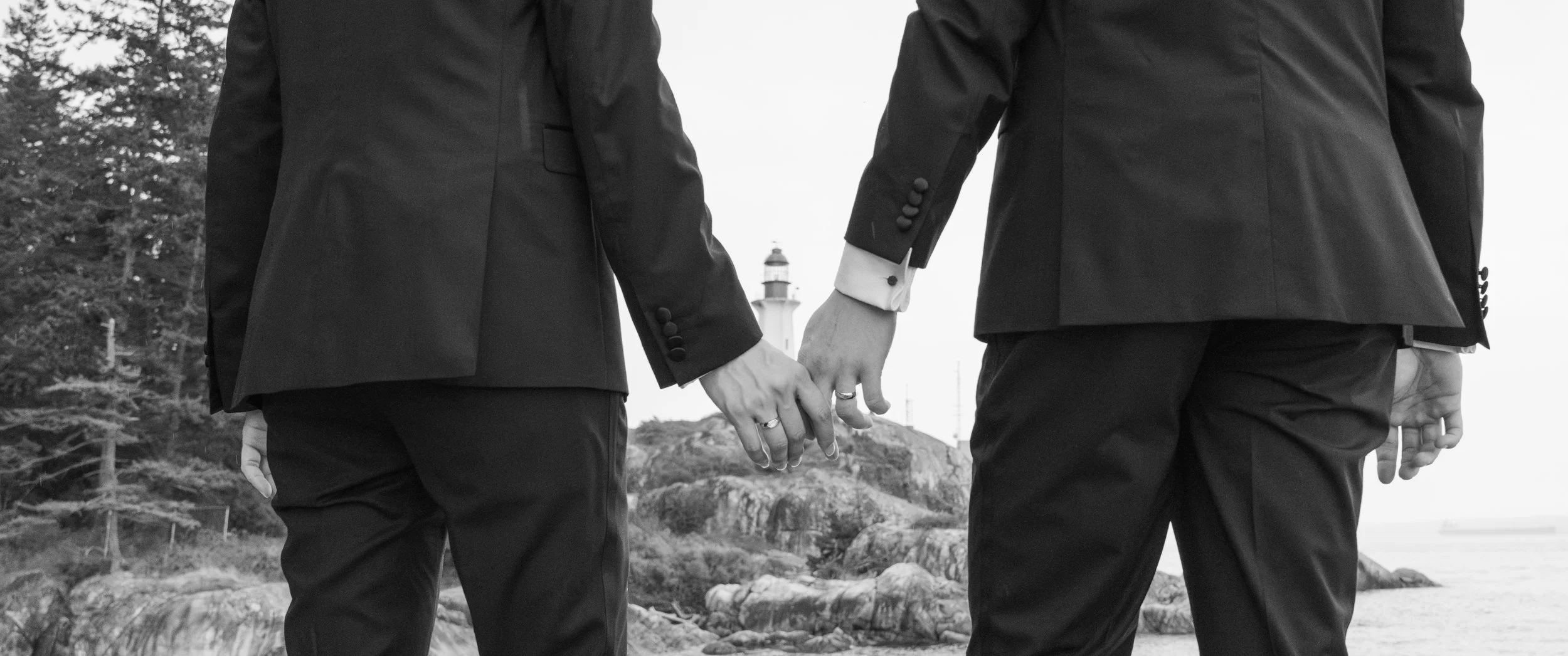 Black and white engagement portrait with a lighthouse in the distance