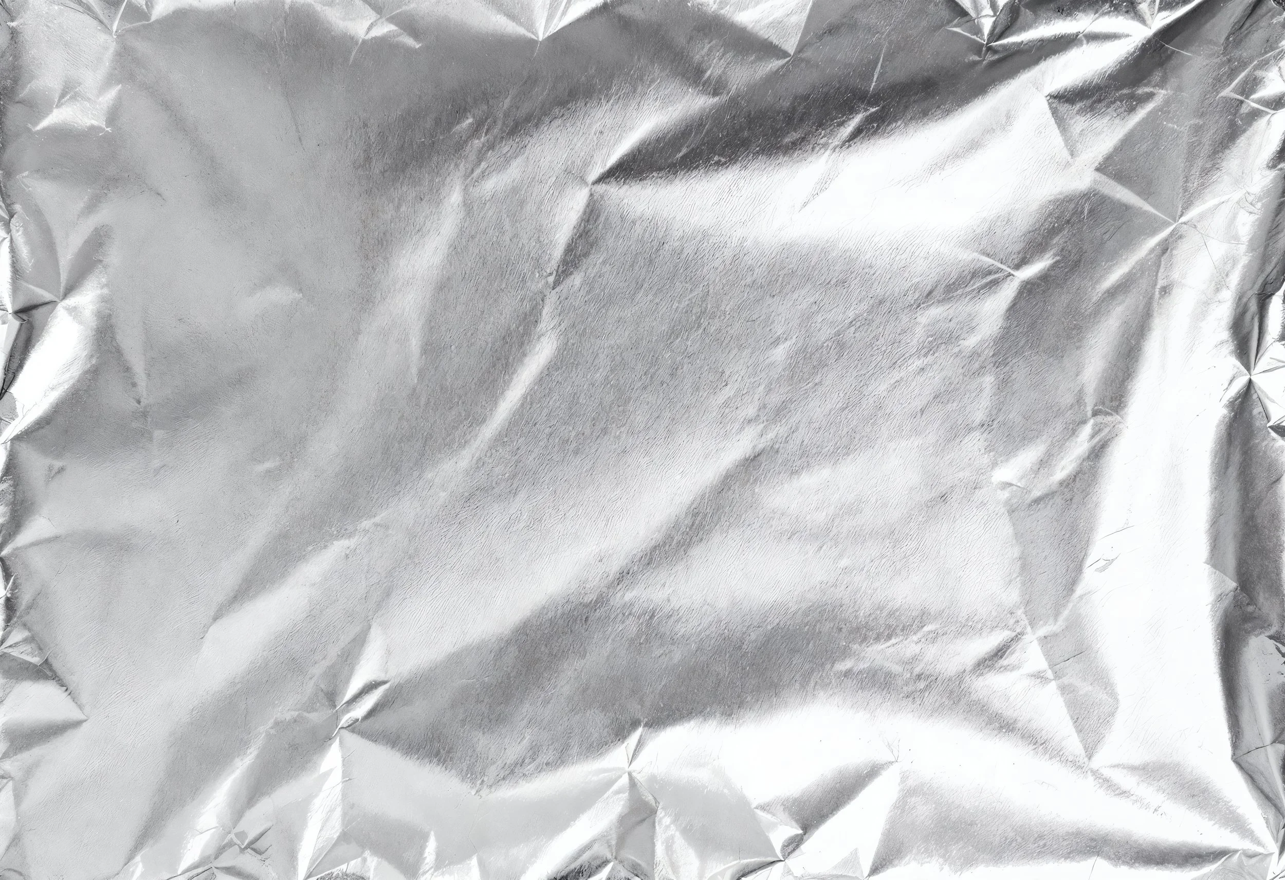 Crinkled silver aluminum foil with reflective surface and textured wrinkles.