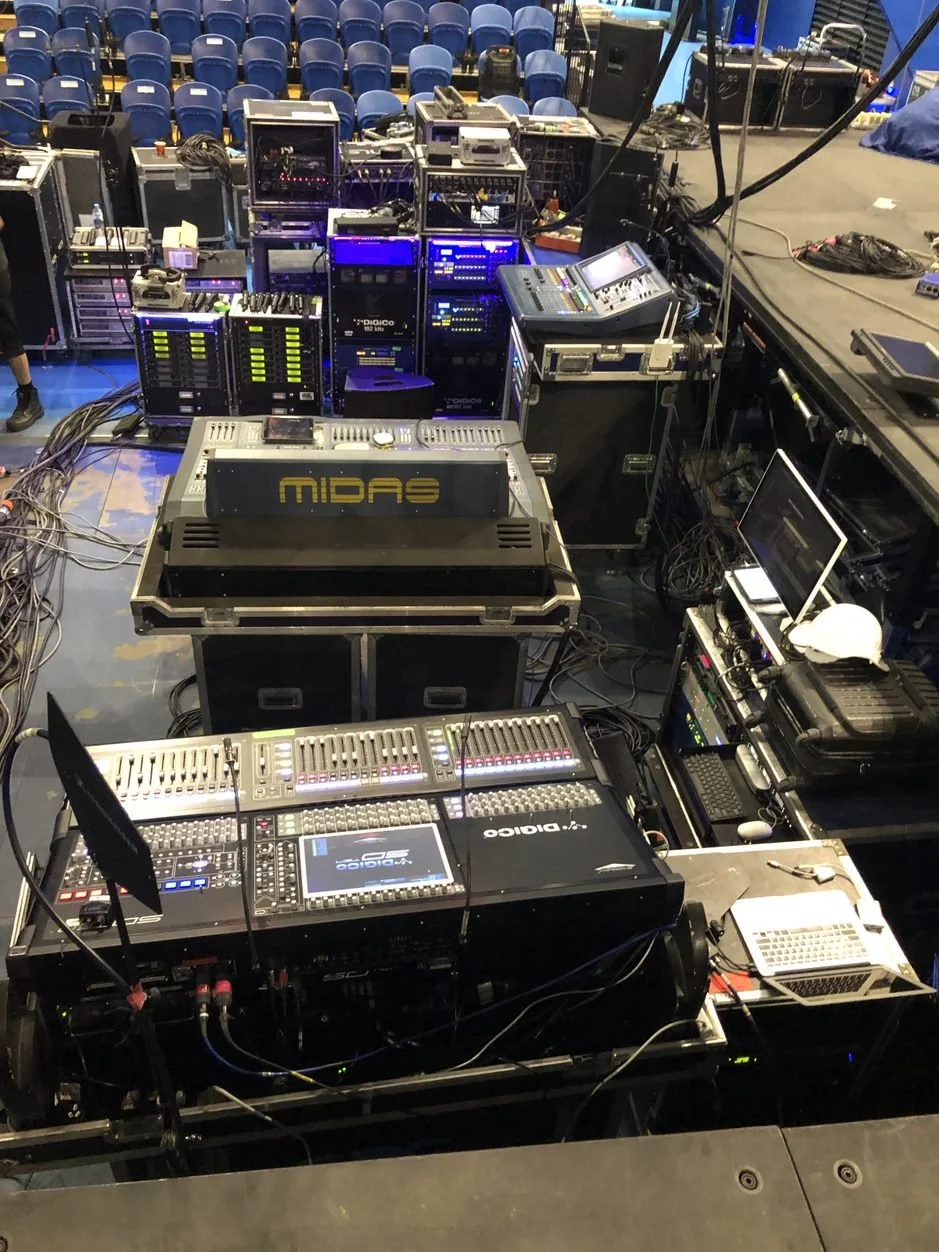 Sound and lighting equipment setup backstage with mixing consoles and digital interfaces.