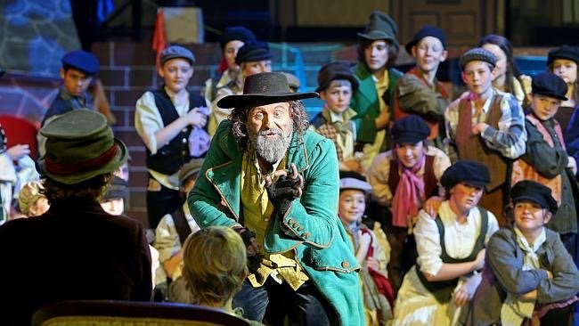 Stage performance of "Oliver Twist" with actor depicting Fagin and children as street urchins.